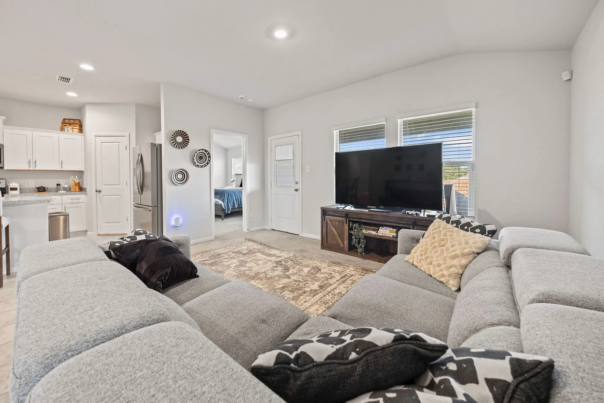 Living area featuring vaulted ceiling, recessed lighting, and light colored carpet