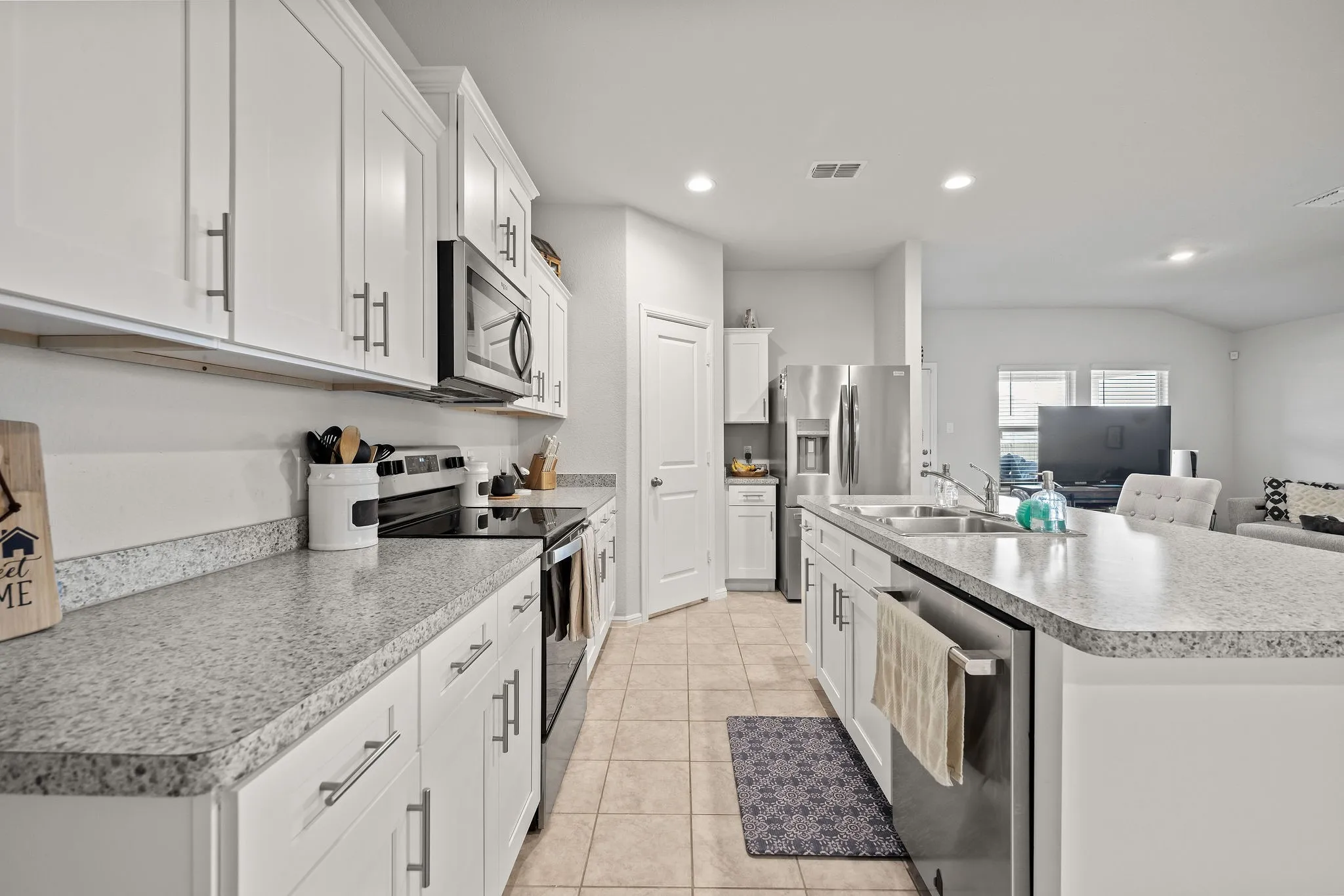 Kitchen featuring appliances with stainless steel finishes, an island with sink, white cabinetry, recessed lighting, and light tile patterned flooring