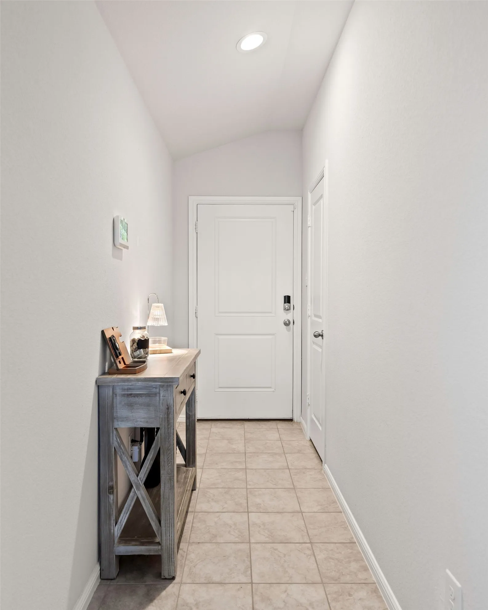 Corridor featuring light tile patterned floors, vaulted ceiling, and recessed lighting