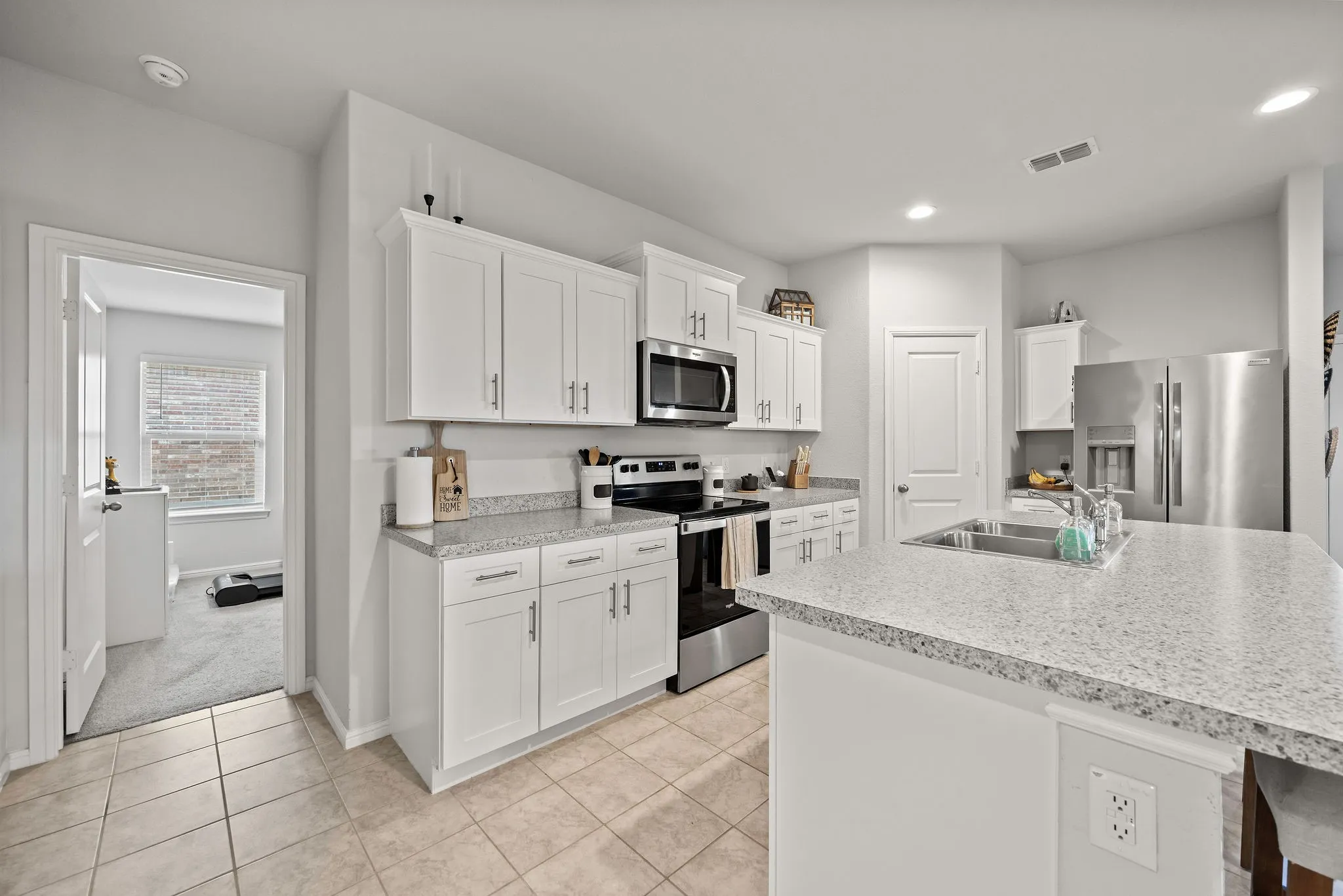 Kitchen with appliances with stainless steel finishes, white cabinets, light countertops, light tile patterned floors, and recessed lighting