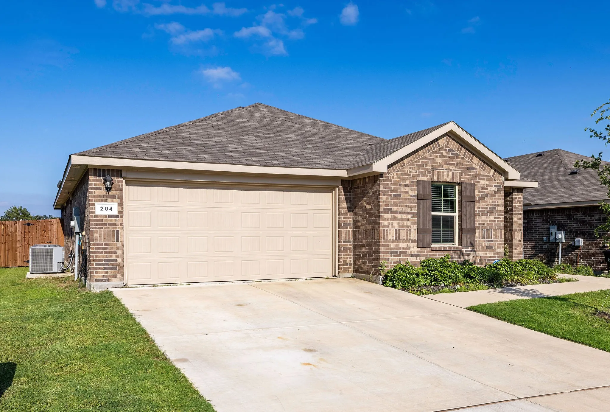 Ranch-style house with brick siding, driveway, an attached garage, and roof with shingles