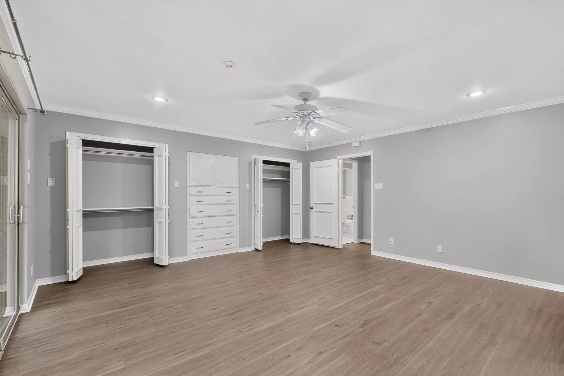 Spacious room featuring wood-finish flooring, recessed lighting, a ceiling fan, and built-in closet storage
