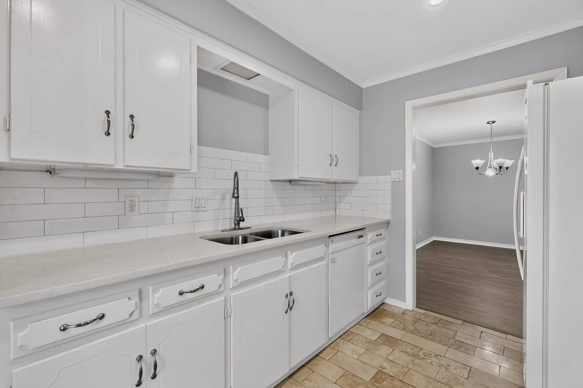 White cabinetry, subway tile backsplash, dual basin sink, and tile flooring