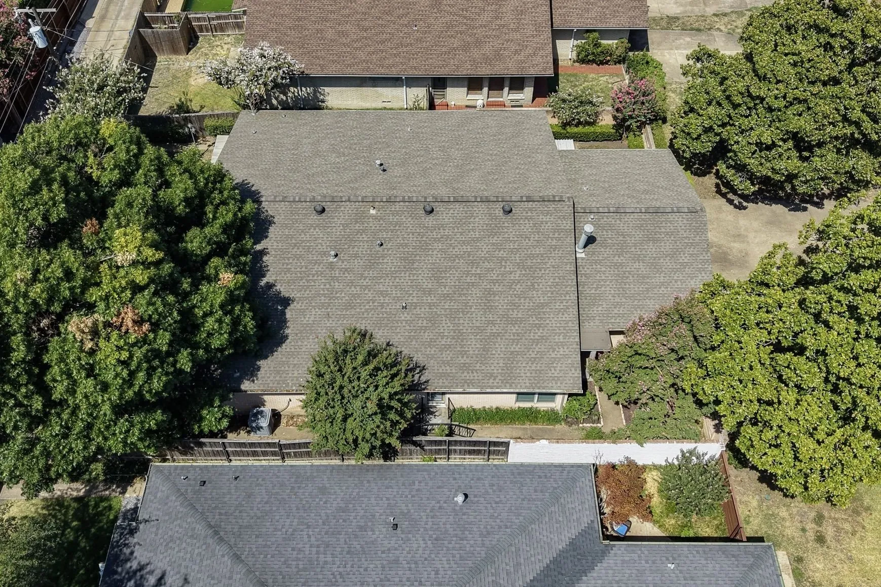 Gray shingle roofing with multiple mature trees