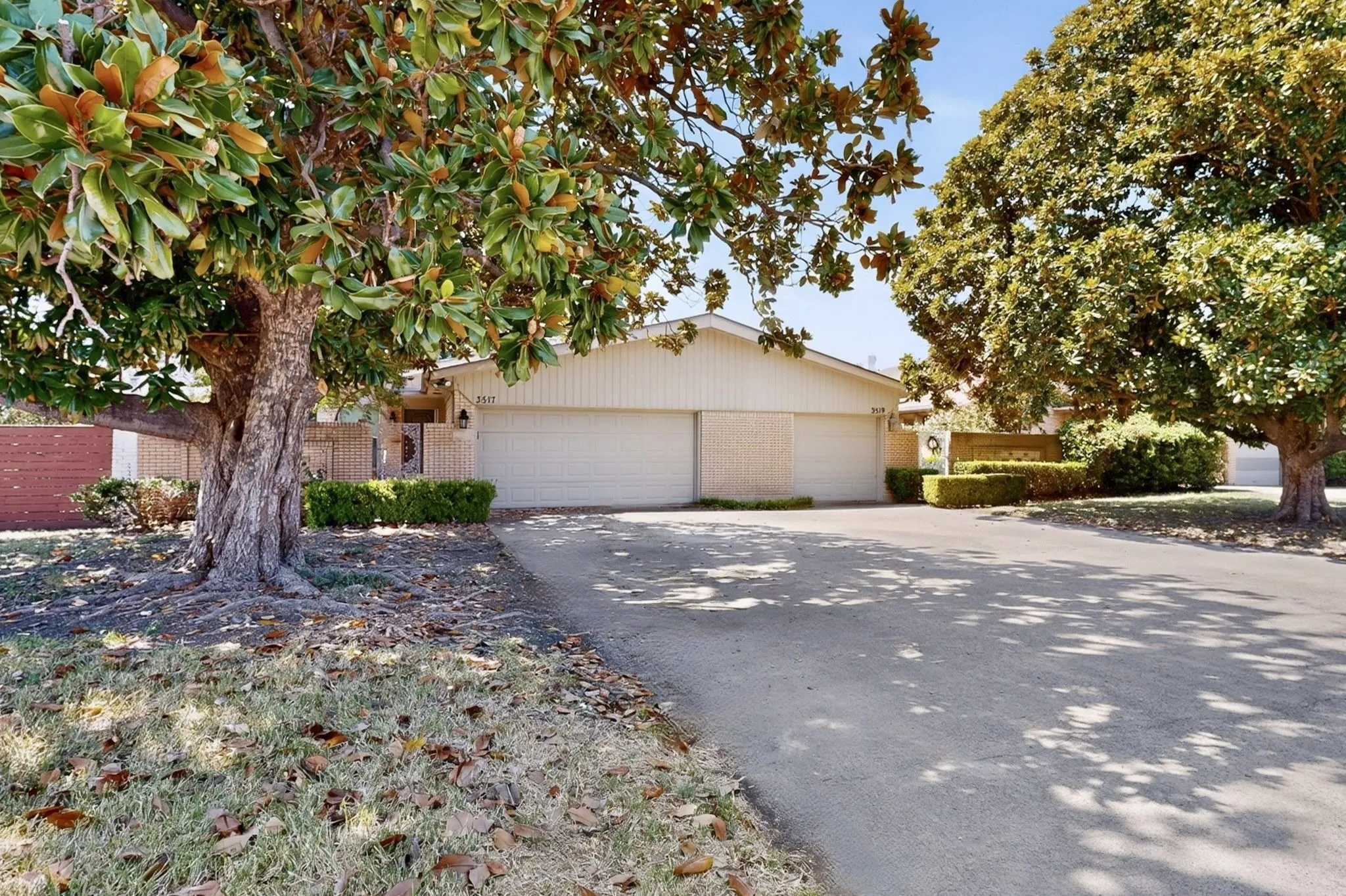 Property exterior with a wide driveway, attached garage, and mature trees