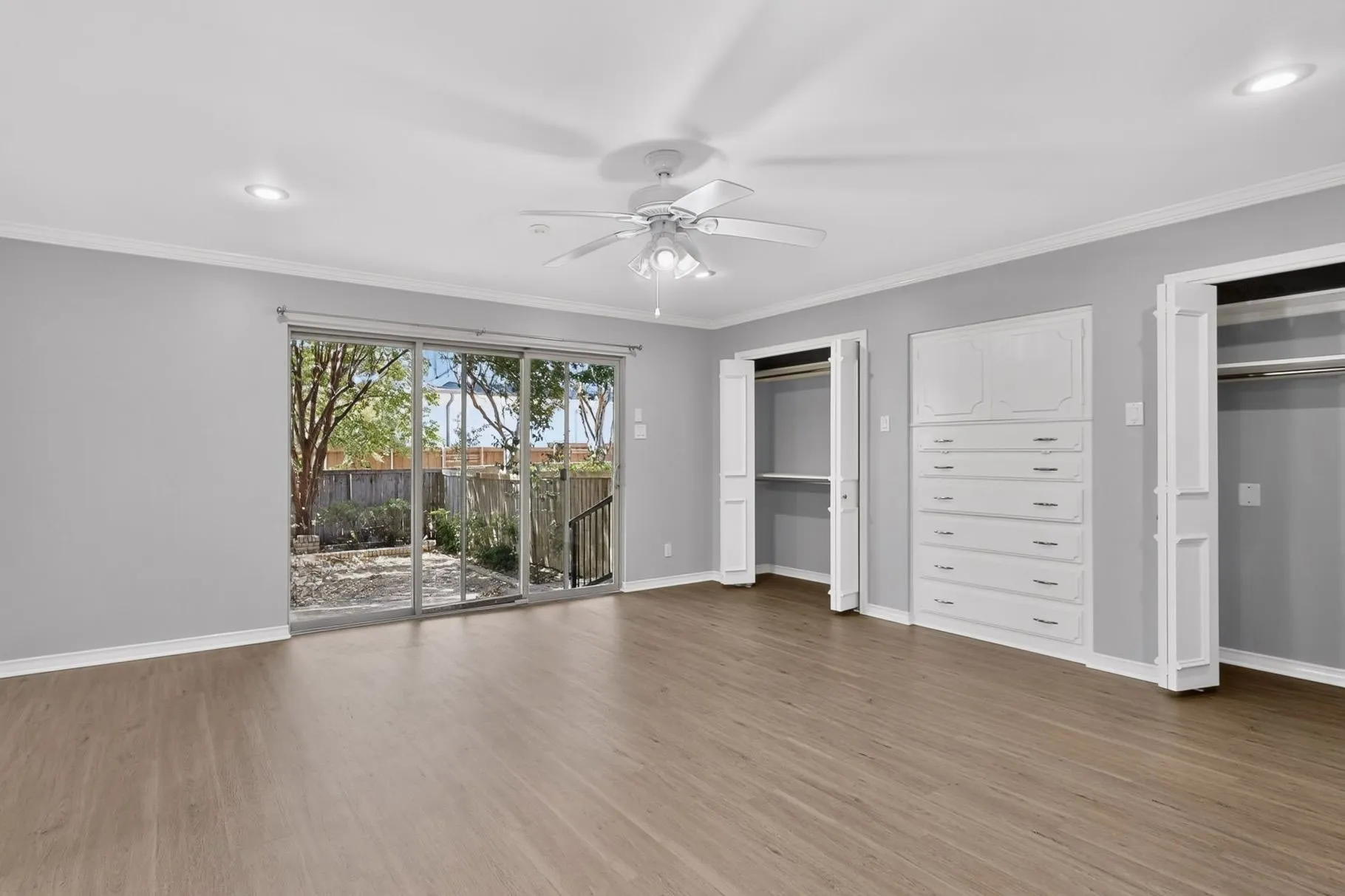Wood-finish flooring, sliding glass door, recessed lighting, ceiling fan, and built-in dresser