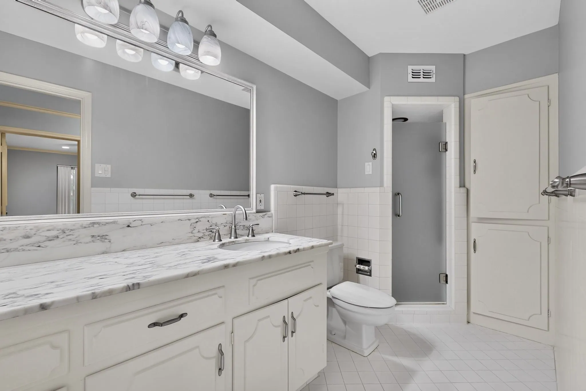Vanity with white-finish cabinetry, integrated sink, and stone countertop