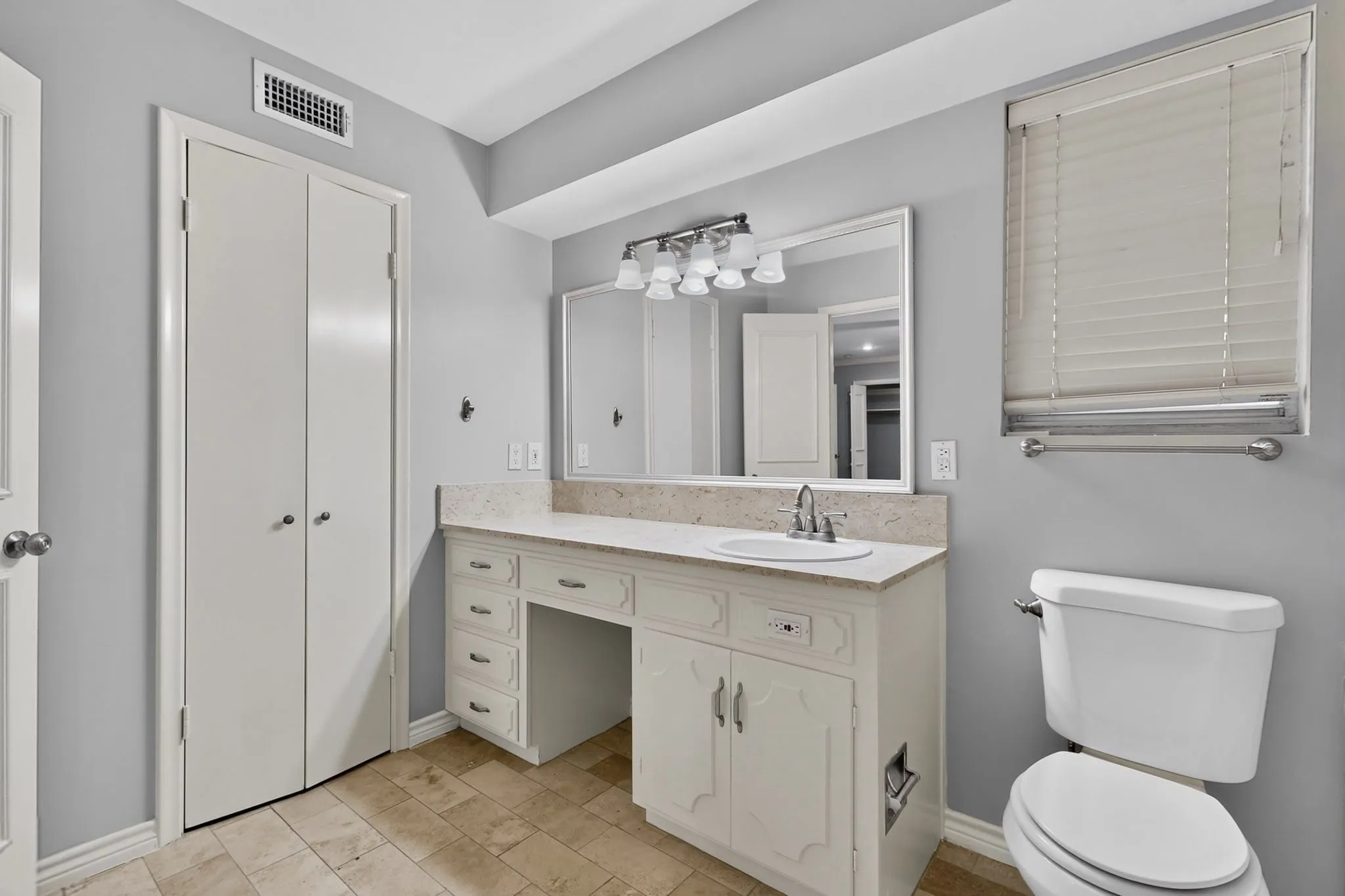 Vanity with integrated sink, stone-finish countertop, and full-width mirror with overhead lighting