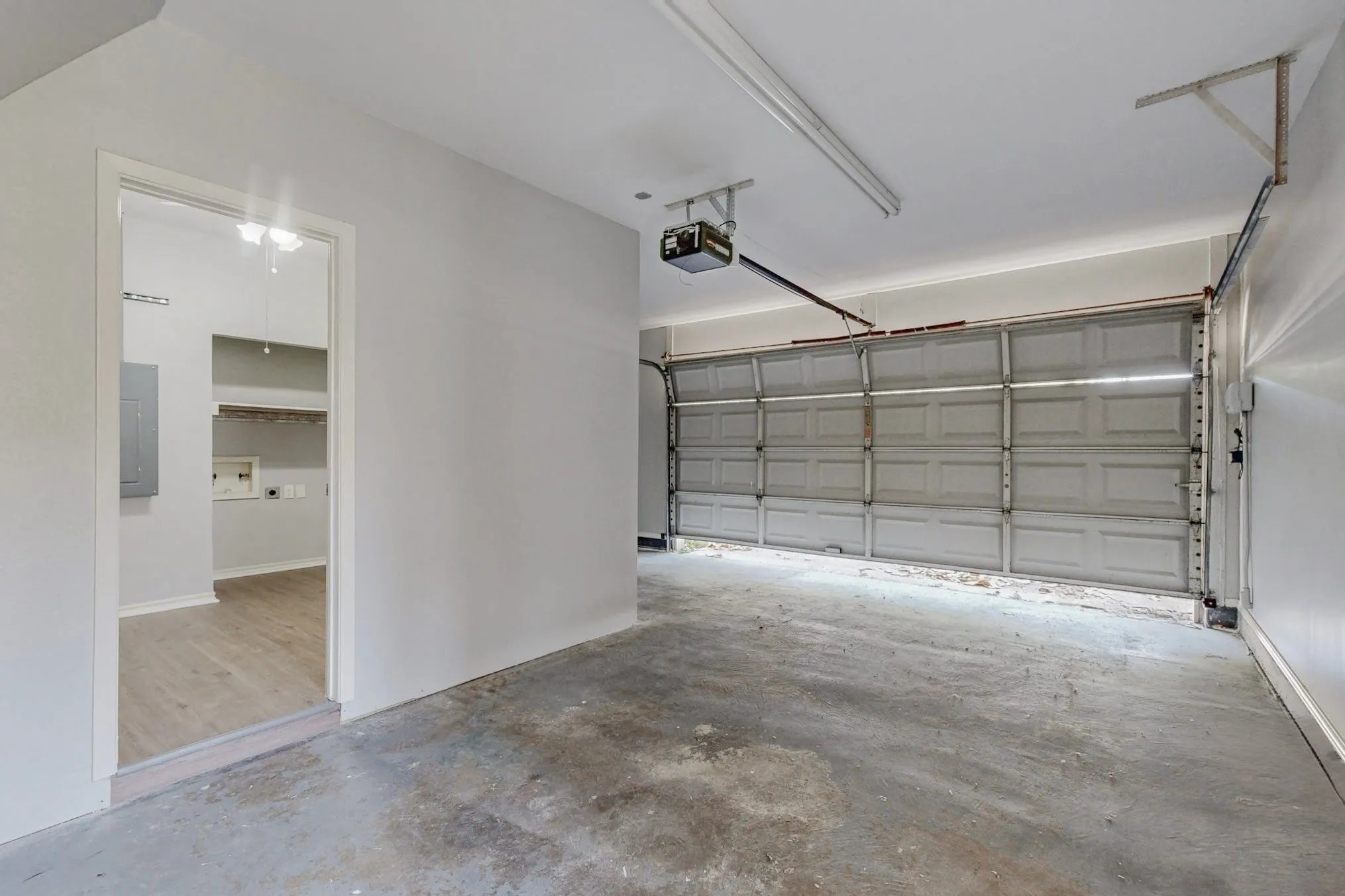 Attached garage with a sectional garage door, concrete flooring, and a garage door opener mechanism