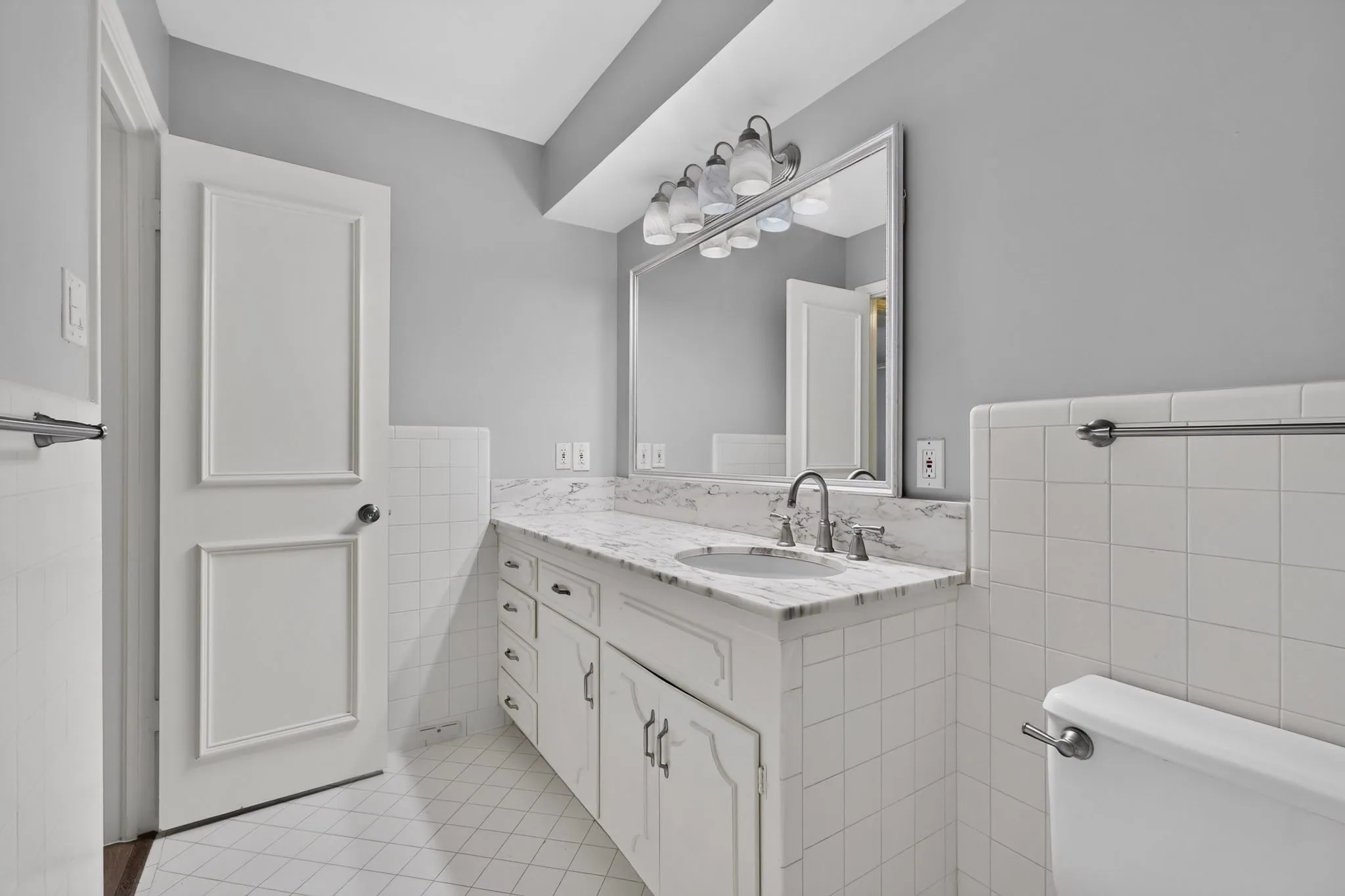 White vanity with integrated sink, polished chrome faucet, and substantial framed mirror