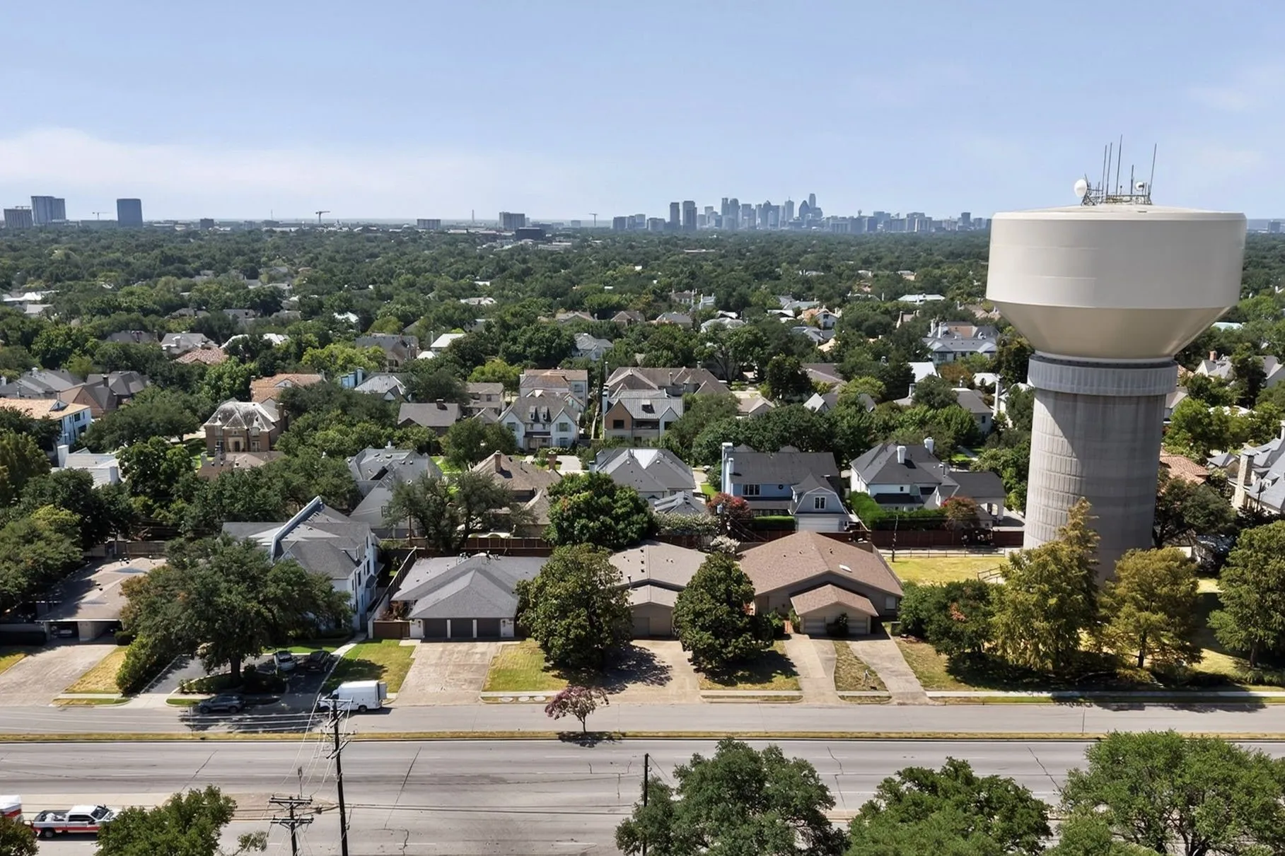 Aerial perspective showcasing an expansive residential area with a prominent water tower and a distant urban skyline