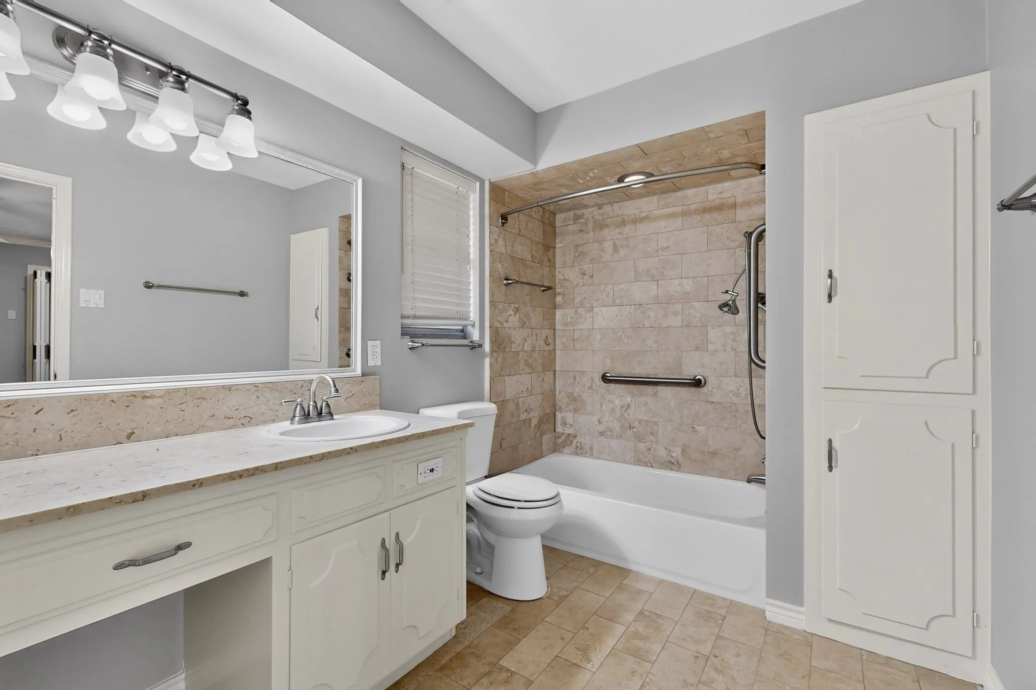 Vanity with integrated sink, stone countertop, and large mirror