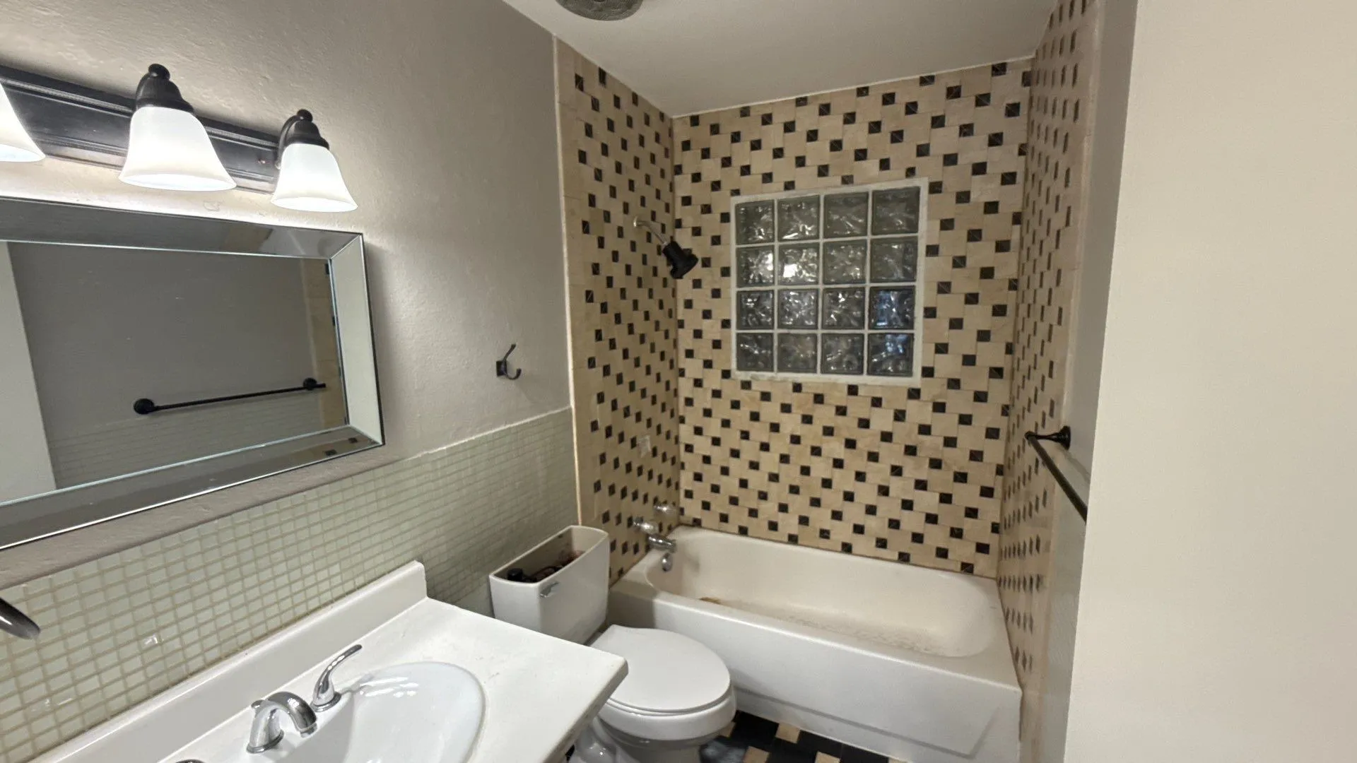 Bathroom featuring a vanity with an integrated sink, a framed mirror, and a three-light fixture