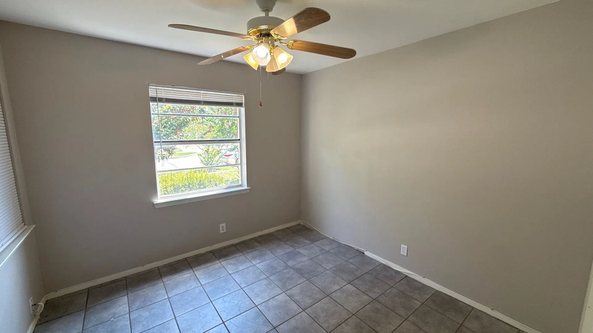 Neutral-toned walls, tile flooring, window with blinds, and a ceiling fan with integrated lighting
