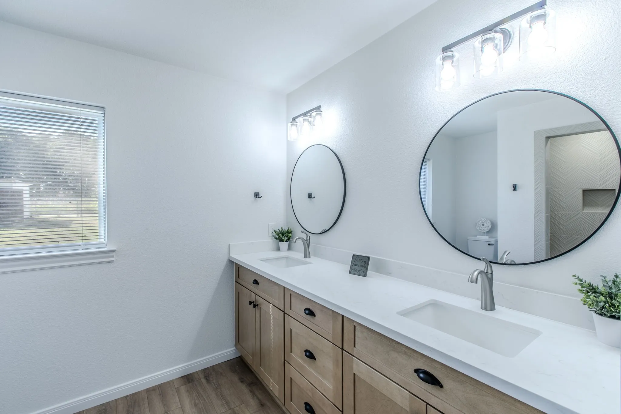 Dual vanity with light wood-finish cabinetry, integrated rectangular sinks, and brushed nickel faucets