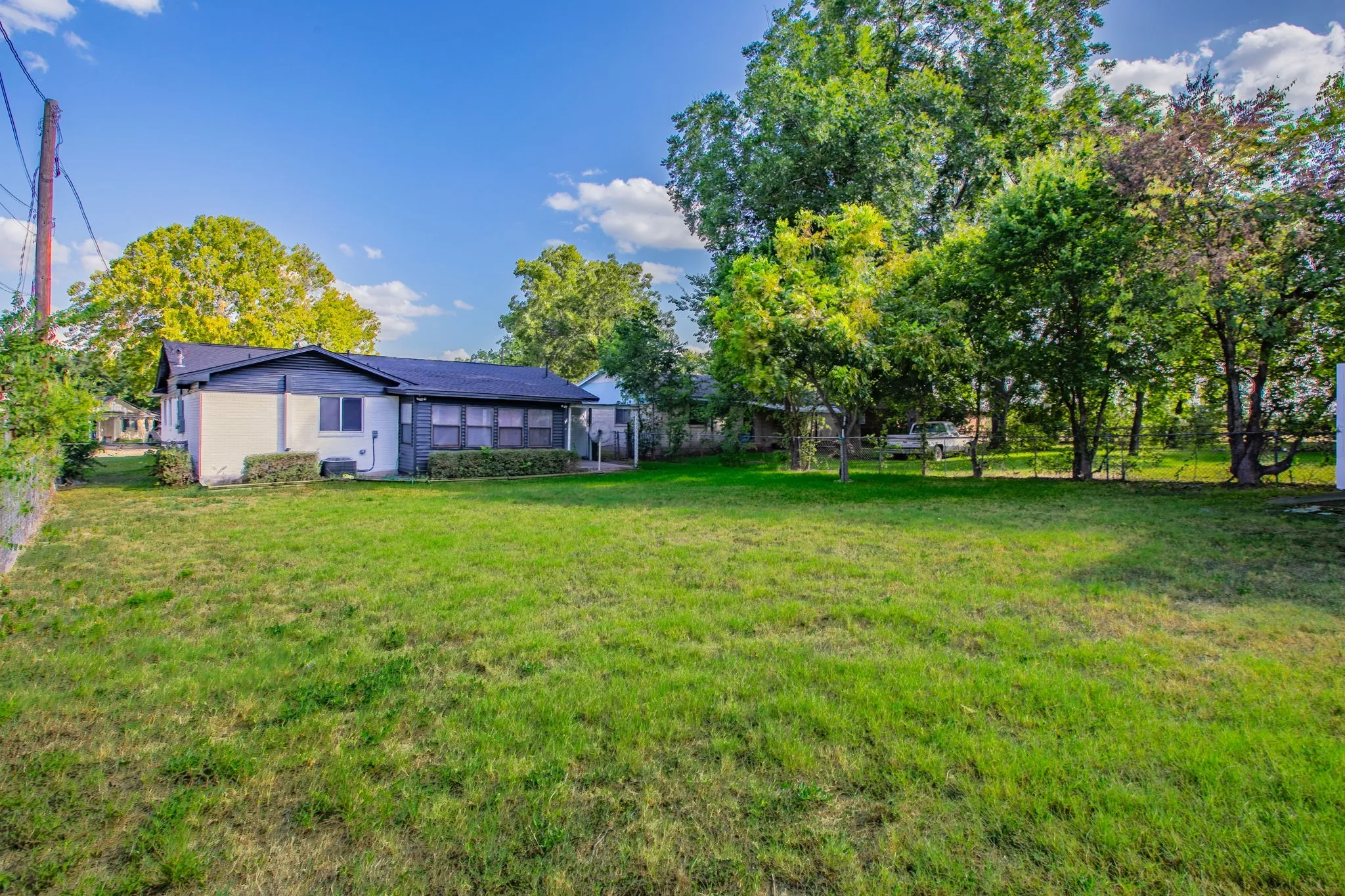 Expansive rear yard featuring a manicured lawn and mature trees