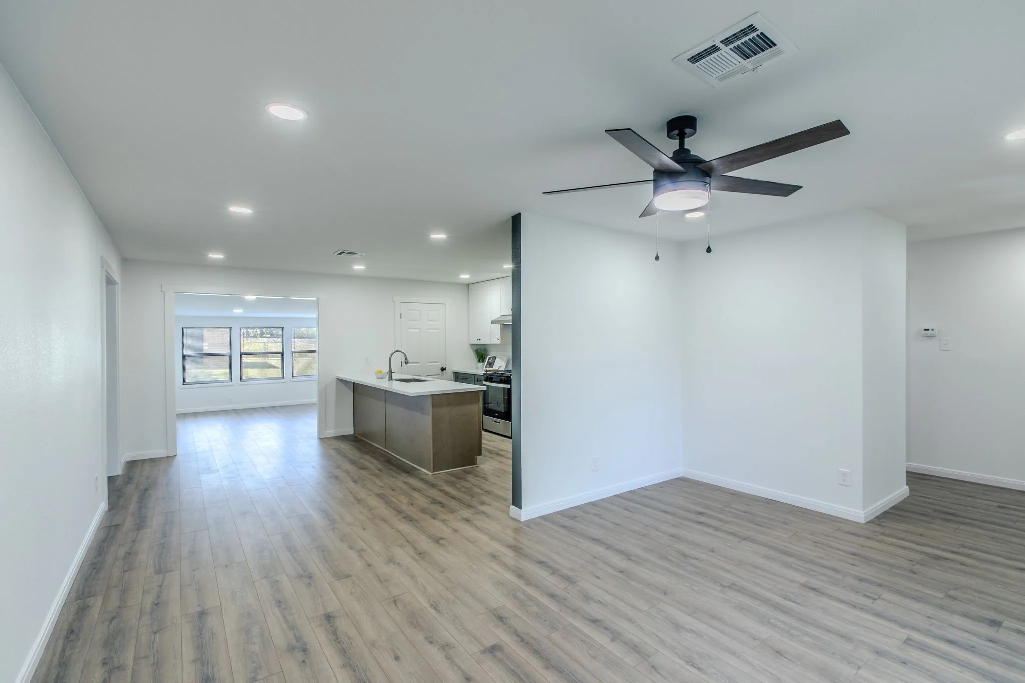 Open-concept living space featuring wood-finish flooring throughout, recessed lighting, and a ceiling fan