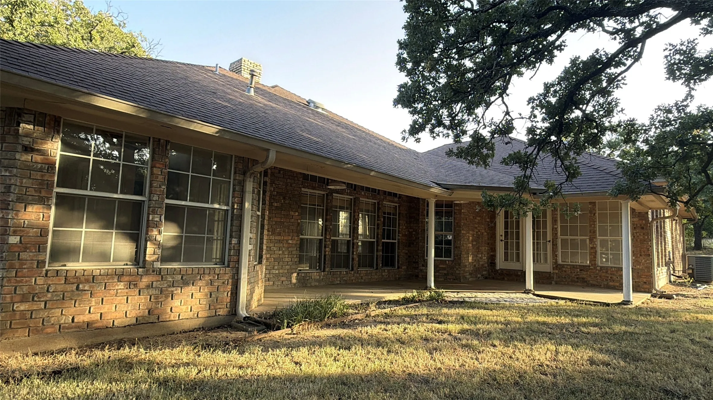 Brick exterior with expansive covered porch featuring multiple large windows and glass-panel doors