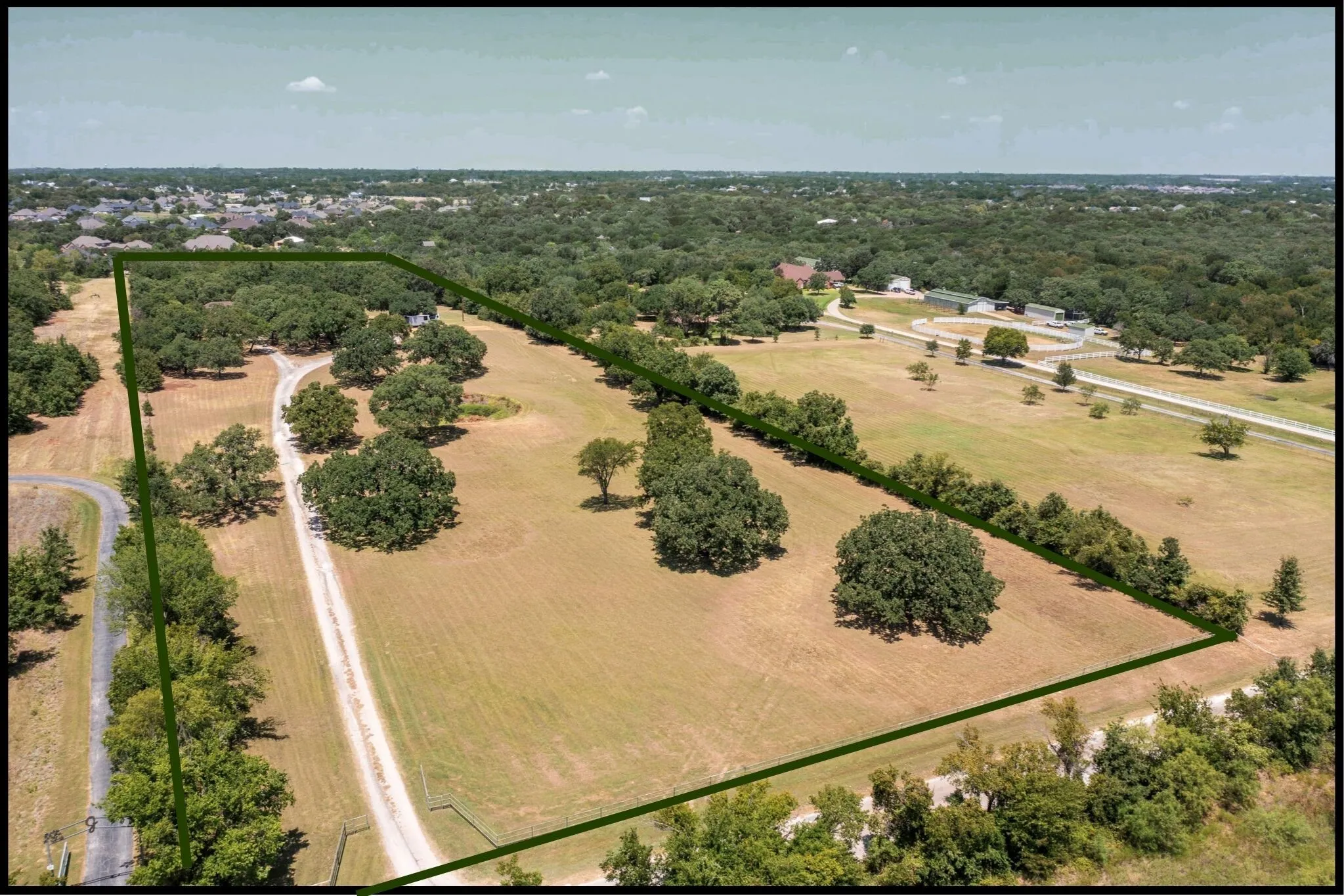 Expansive land parcel featuring mature trees, a private driveway, and clear boundaries