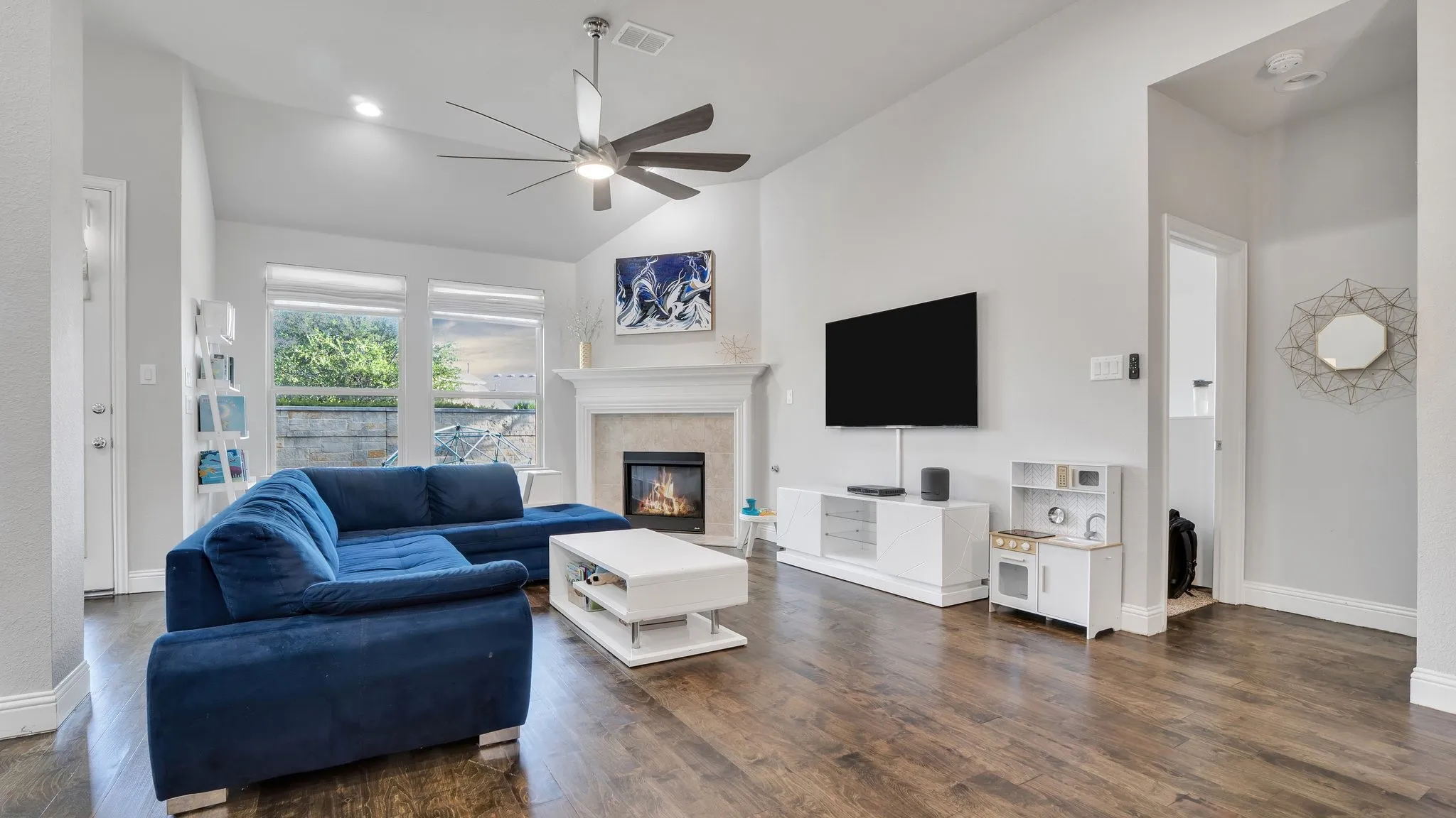 Vaulted ceilings, wood-finish flooring, a fireplace with a mantel, and recessed lighting