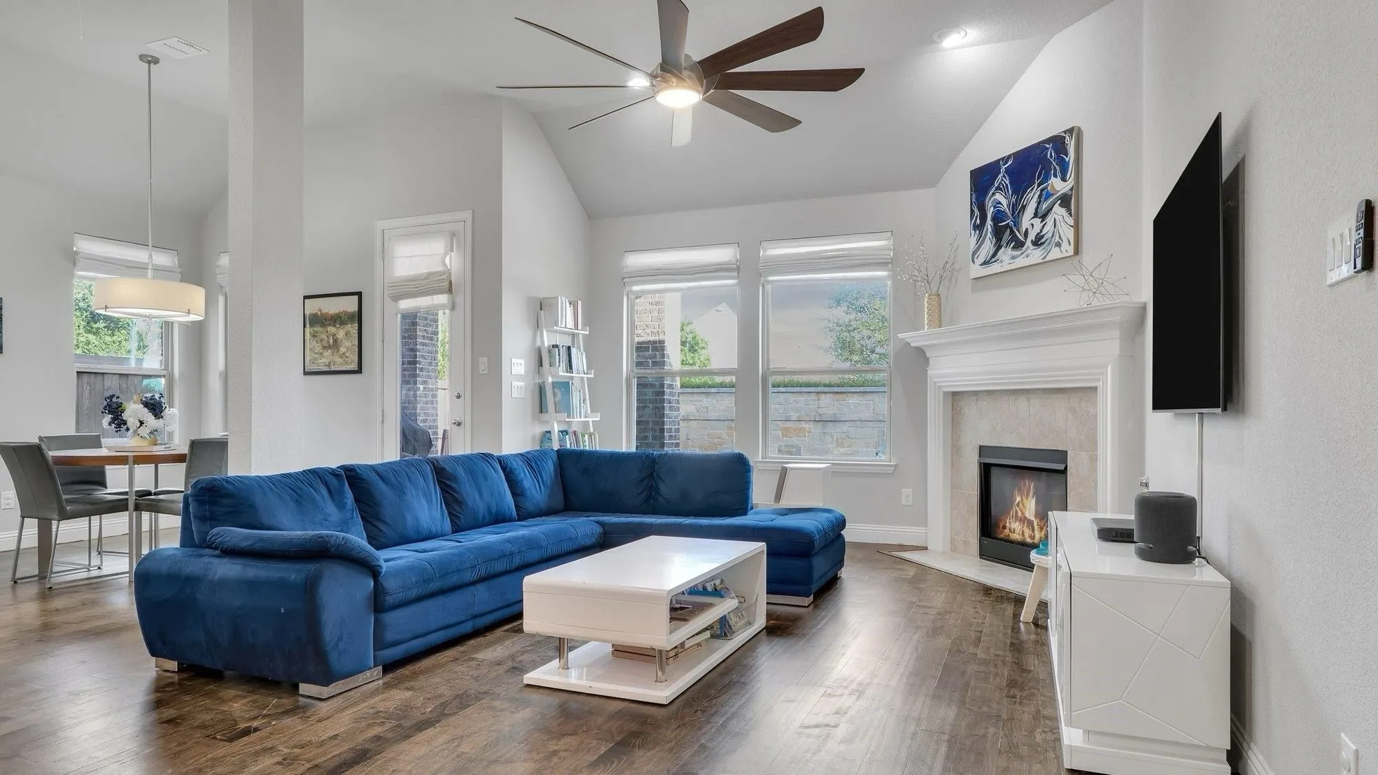 Vaulted ceilings, wood-finish flooring, built-in fireplace with mantel, ceiling fan, and pendant lighting