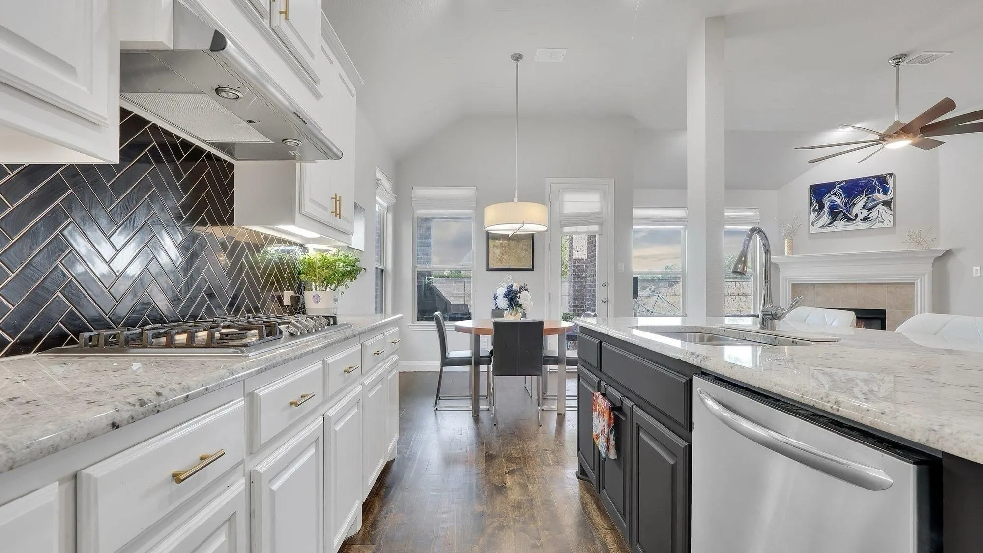 Gourmet kitchen featuring granite countertops, a herringbone tile backsplash, stainless steel appliances, and white cabinetry with gold-tone hardware