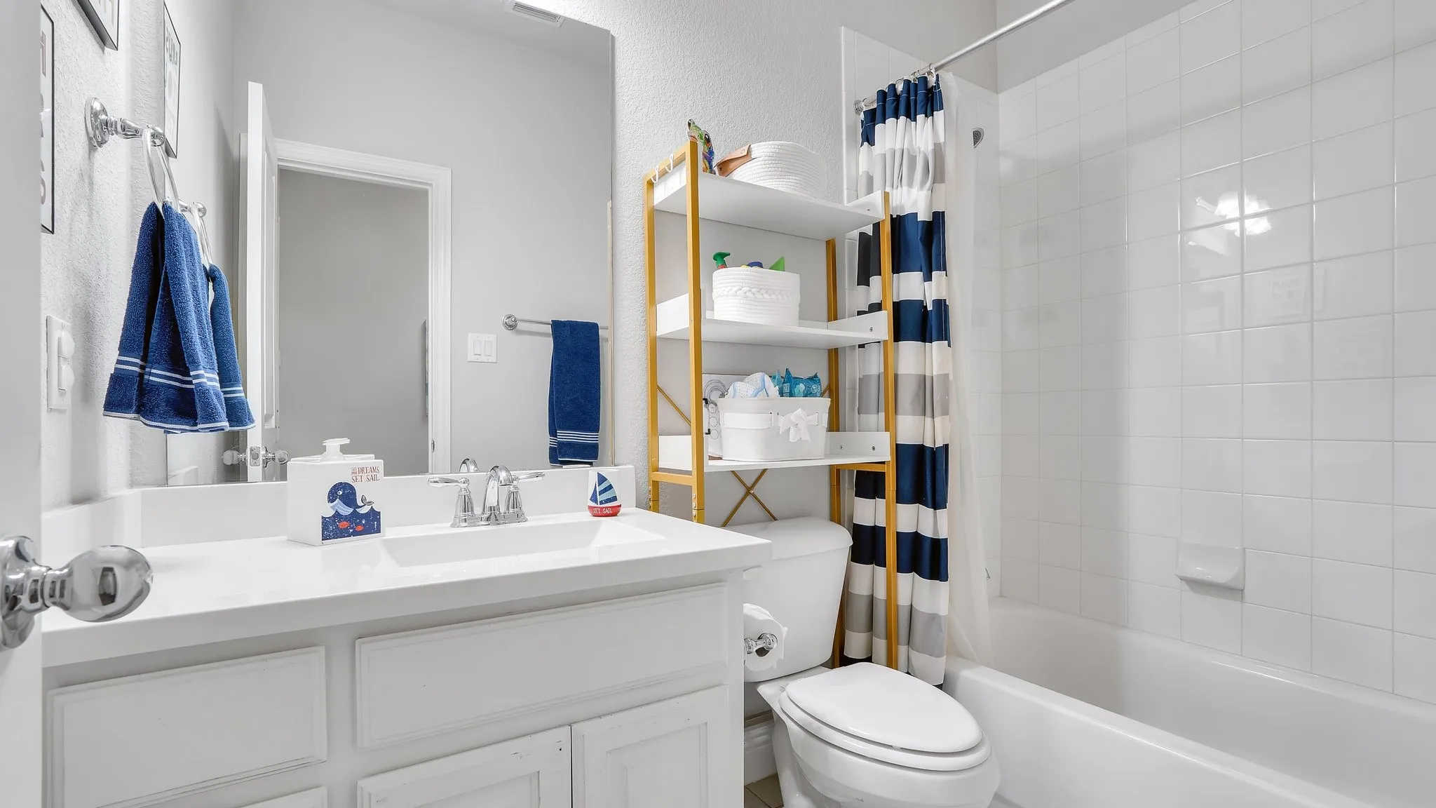 White vanity with a built-in sink, chrome fixtures, and a large wall-mounted mirror