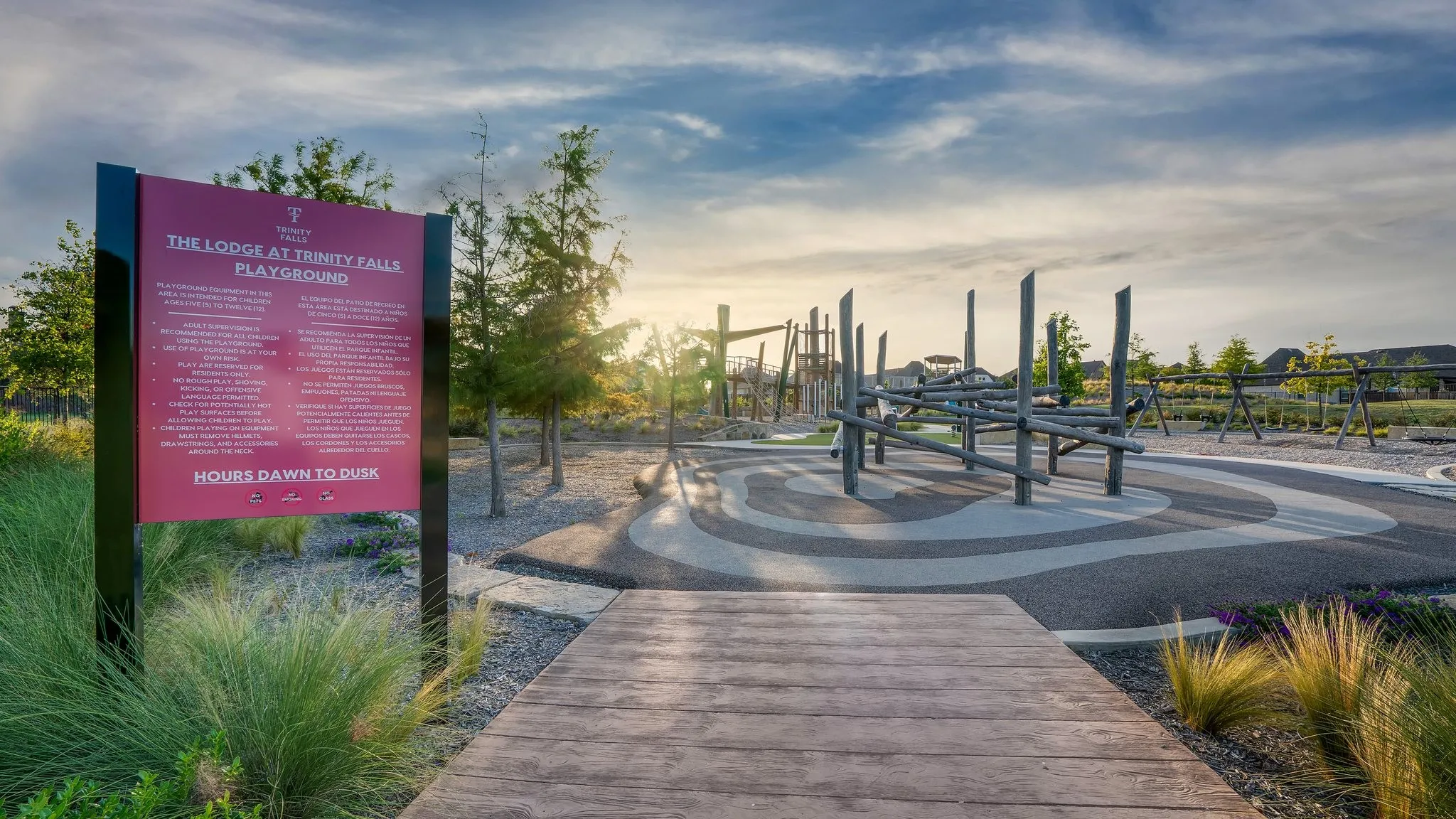 Community playground featuring wood-finish play structures, specialized ground surfacing, and mature landscaping