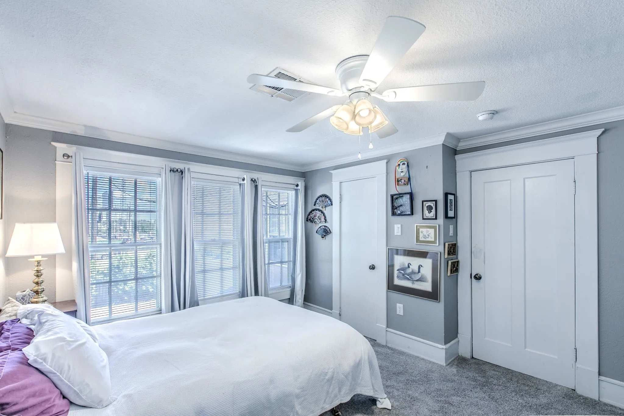 Room featuring three multi-pane windows, a ceiling fan with integrated lighting, and two panel doors