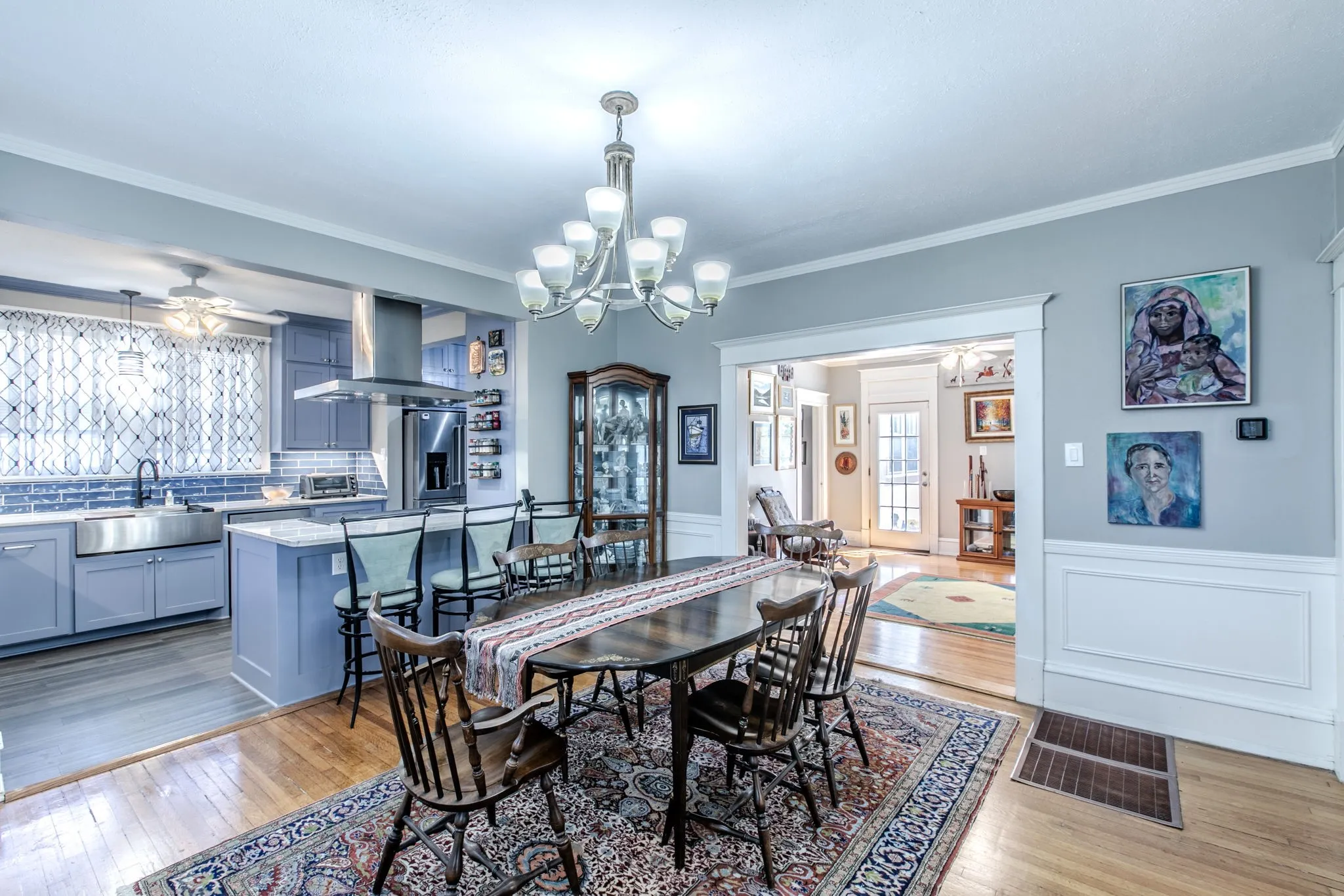 Open-concept living space featuring wood-finish flooring, a kitchen island with seating, stainless steel appliances, and a farmhouse sink