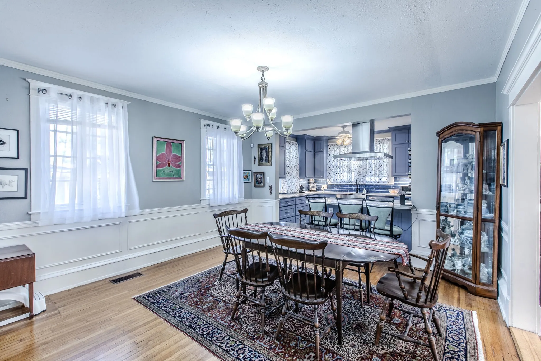 Hardwood flooring extending throughout, with white wainscoting and crown molding