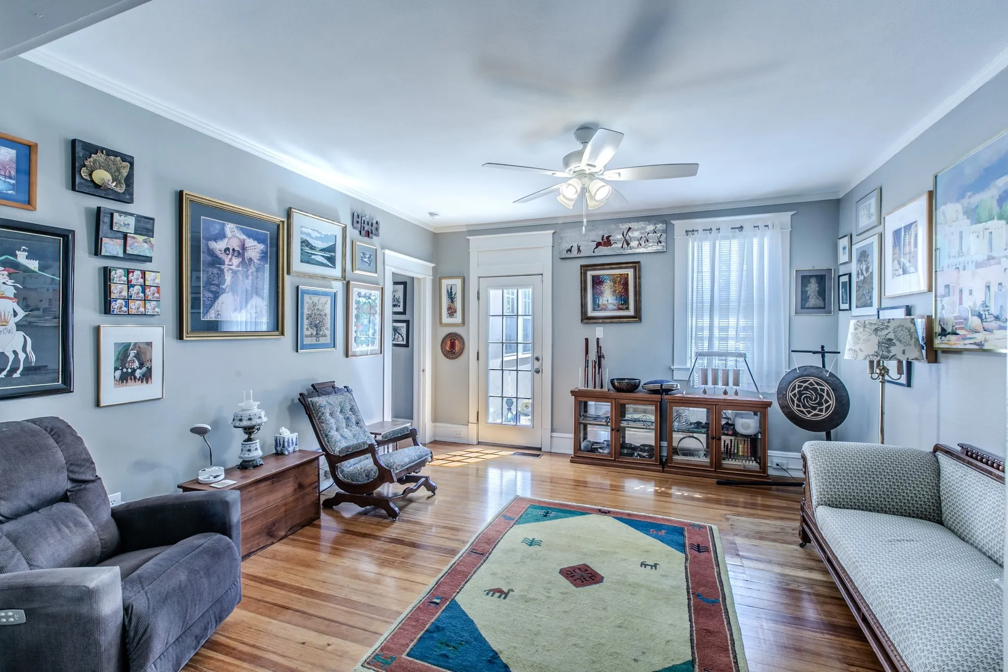 Hardwood flooring, crown molding, white trim, ceiling fan, and French doors