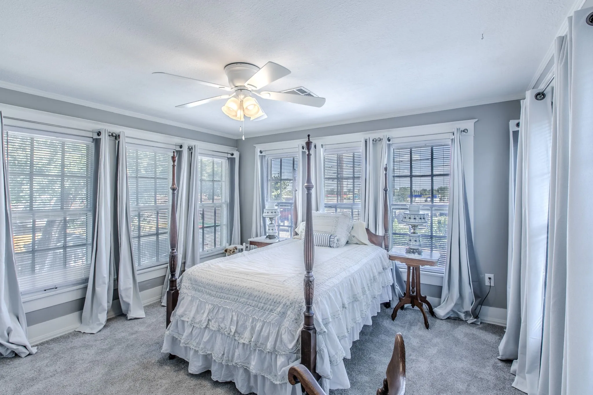 Room featuring multiple windows, crown molding, a ceiling fan with integrated lighting, and carpet flooring