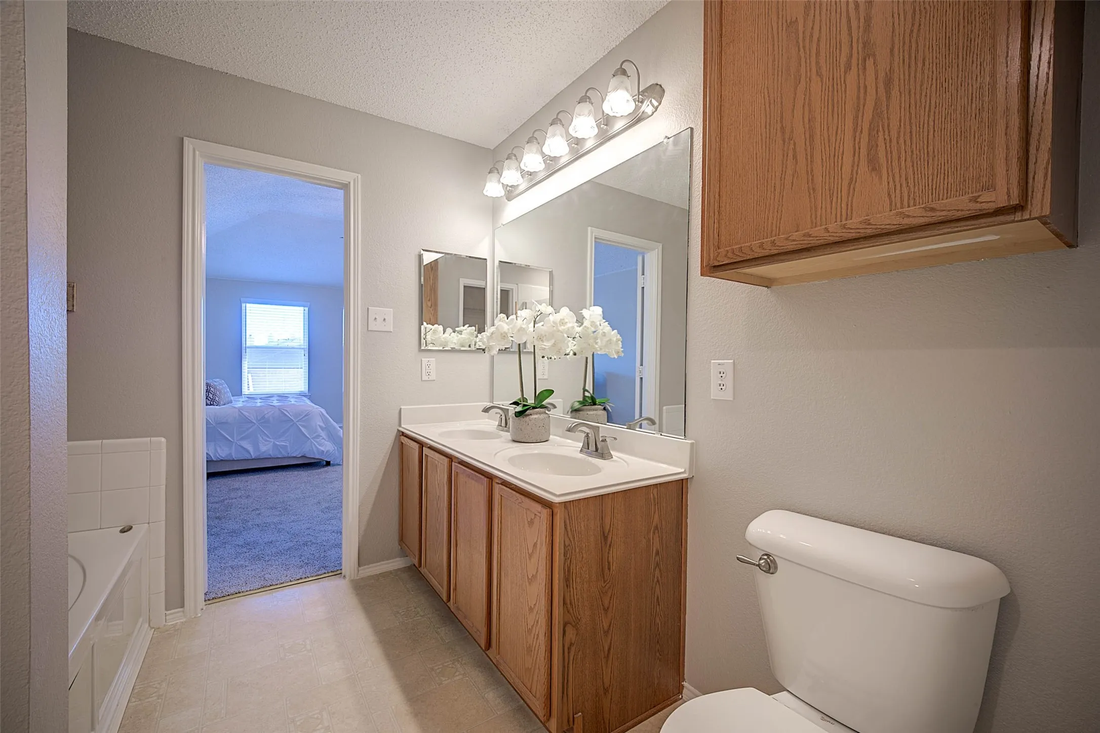 Double vanity with undermount sinks, wood-finish cabinetry, and a large mirror