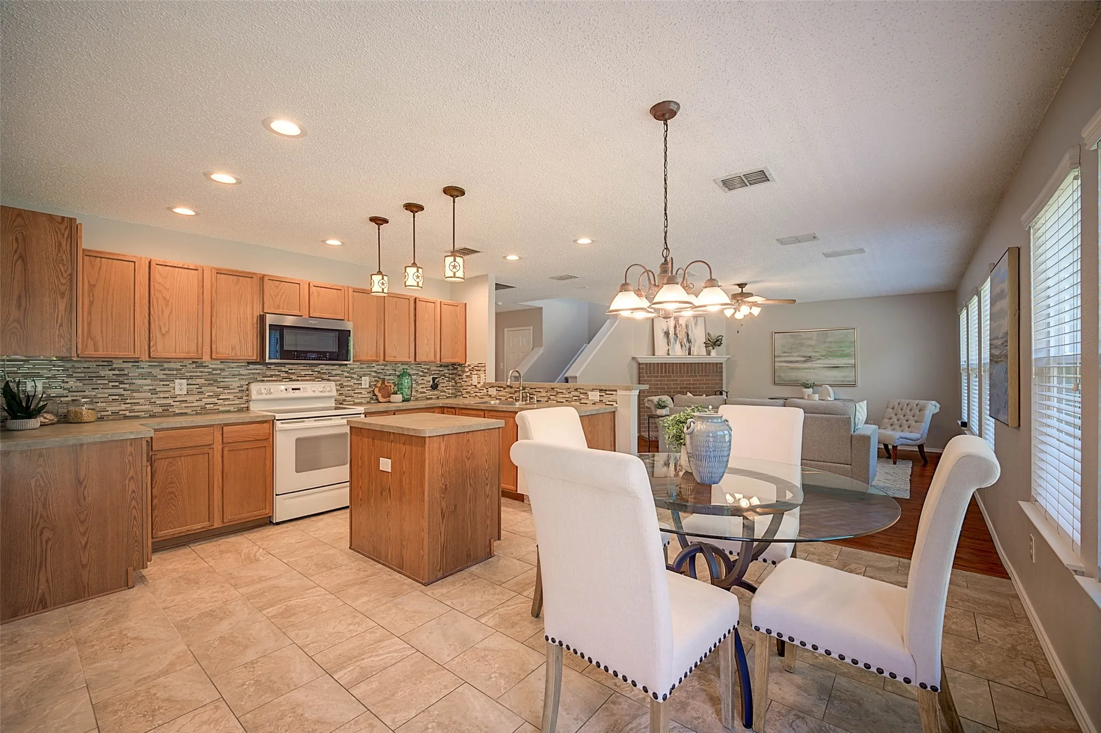 Open-concept living area featuring a kitchen with wood cabinetry, a tile backsplash, and a central island