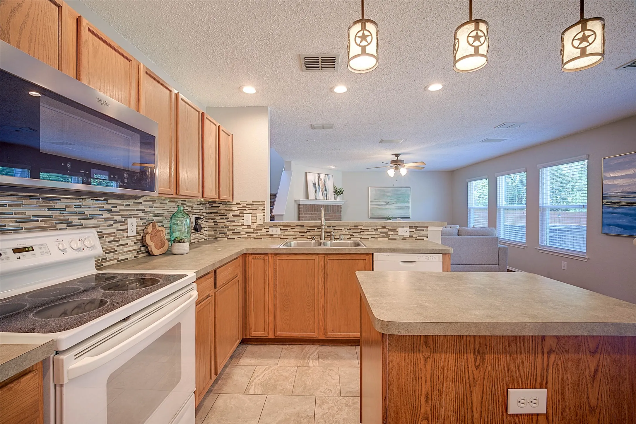 Kitchen featuring wood cabinetry, a patterned tile backsplash, stainless steel microwave, and integrated dishwasher