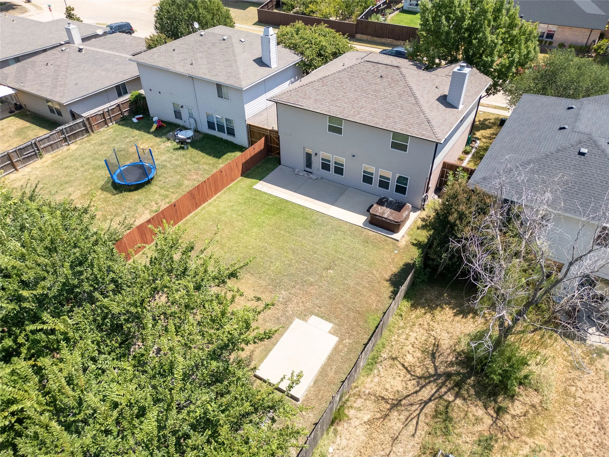 Expansive backyard featuring a concrete patio, a concrete pad, and wood fencing