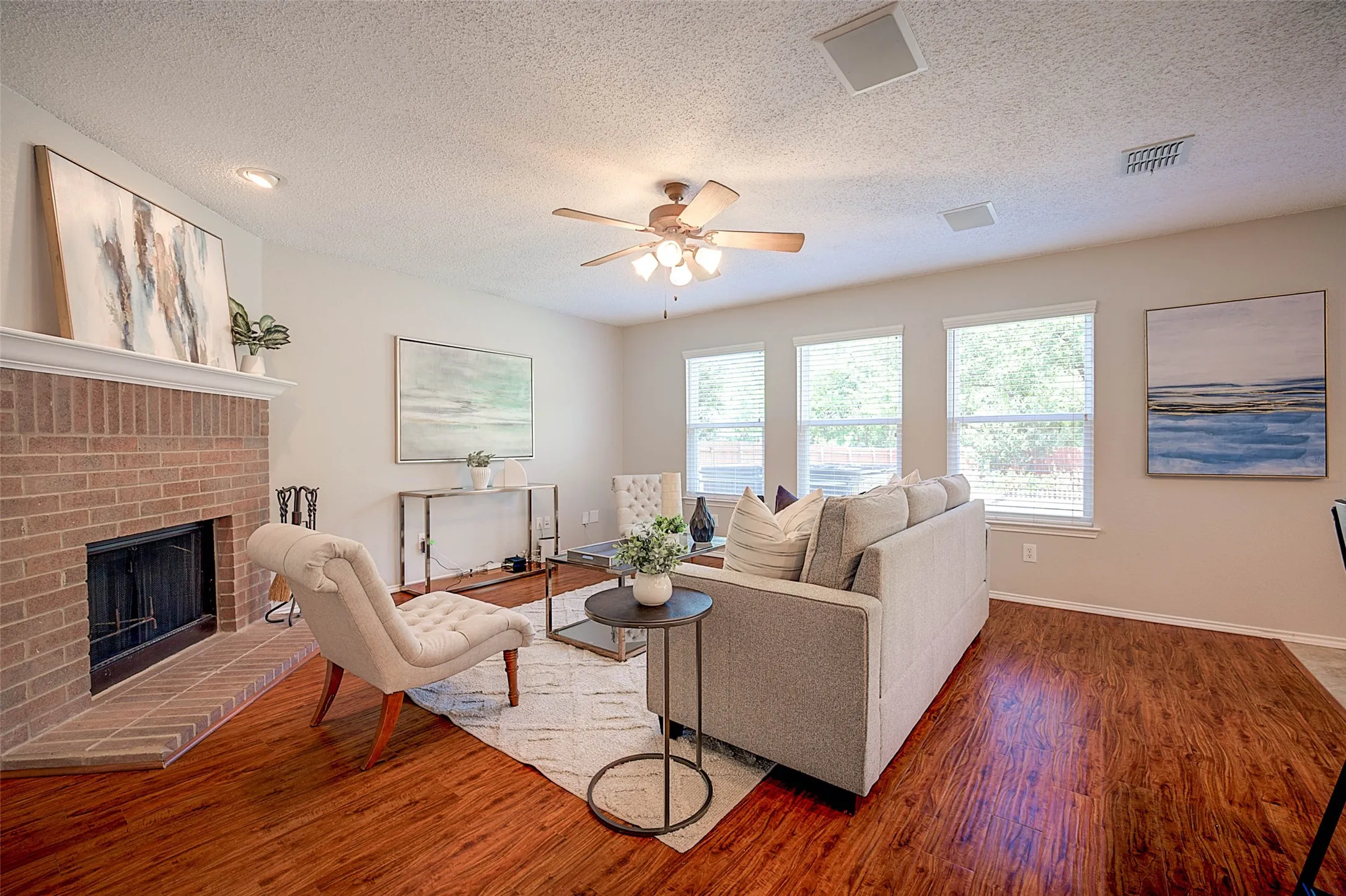 Brick fireplace with a white mantel, wood-finish flooring, recessed lighting, and a ceiling fan