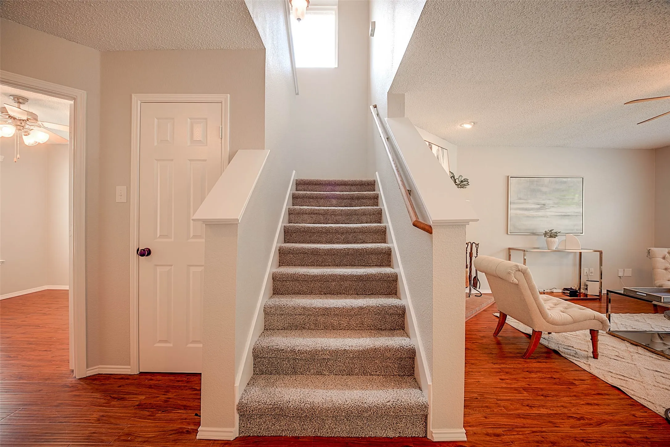 Carpeted staircase with white risers and a wood handrail
