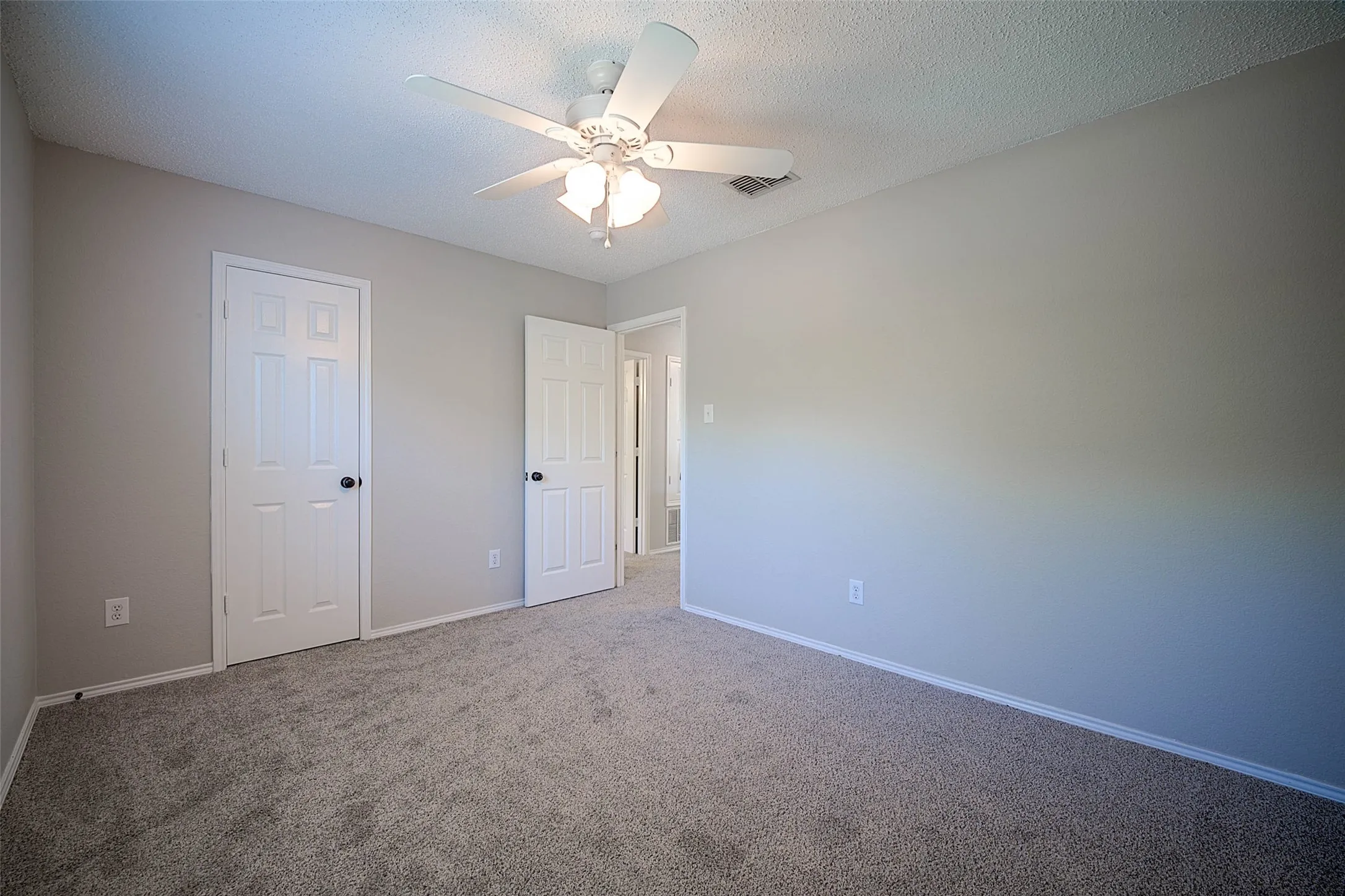 Neutral-toned walls, textured ceiling, and gray carpeted flooring define this room