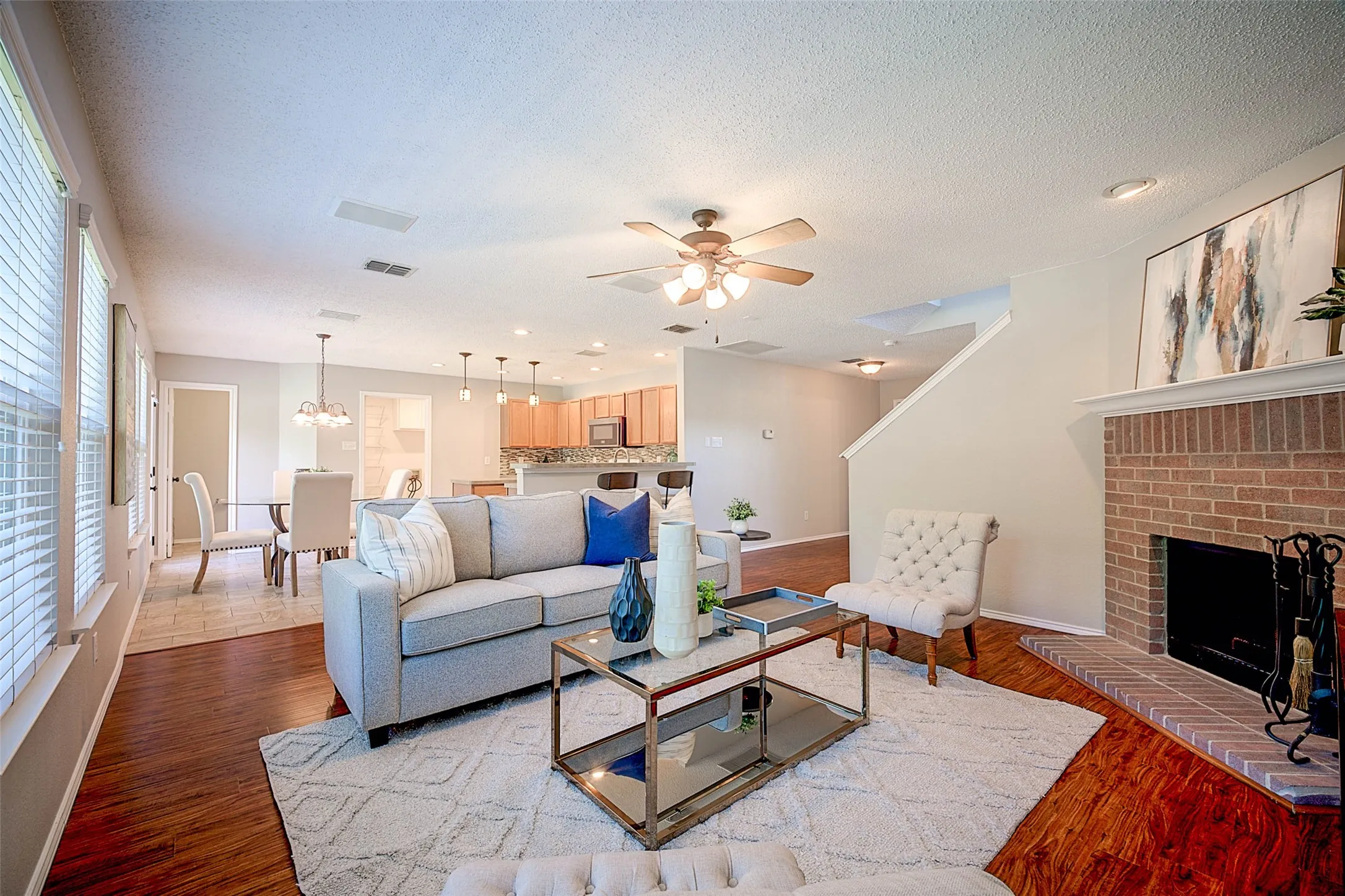 Living area with rich wood-finish flooring, a brick-surround fireplace, and an open layout