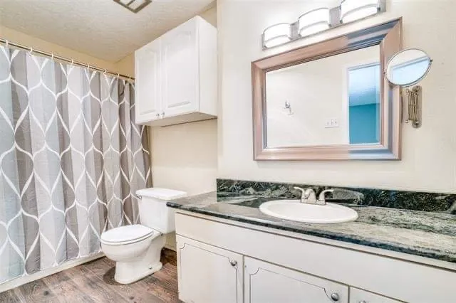 Vanity with dark stone-finish countertop, single-basin sink, and chrome fixtures