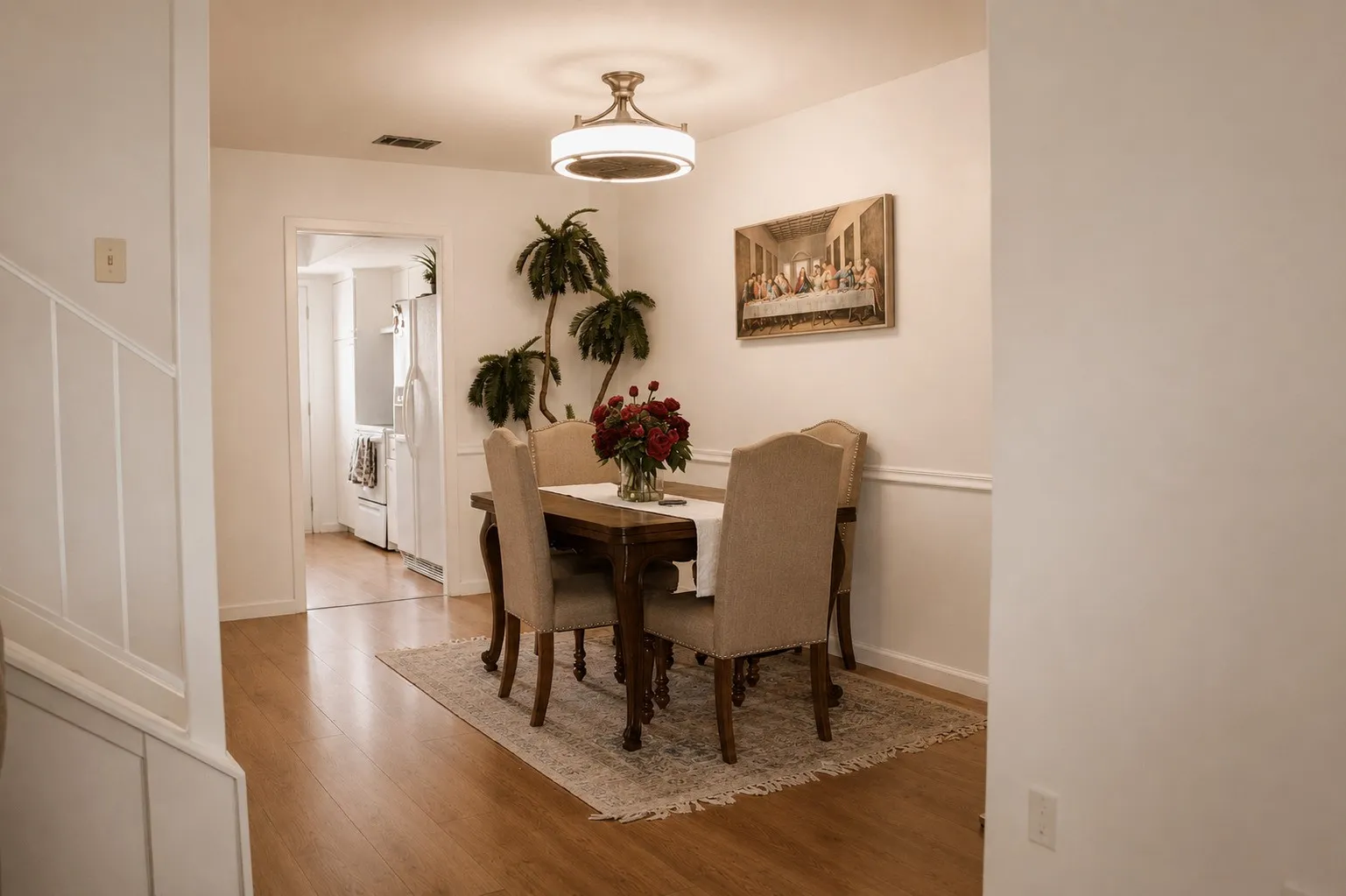 Wood-finish flooring throughout, white wainscoting and crown molding, and a modern ceiling light fixture