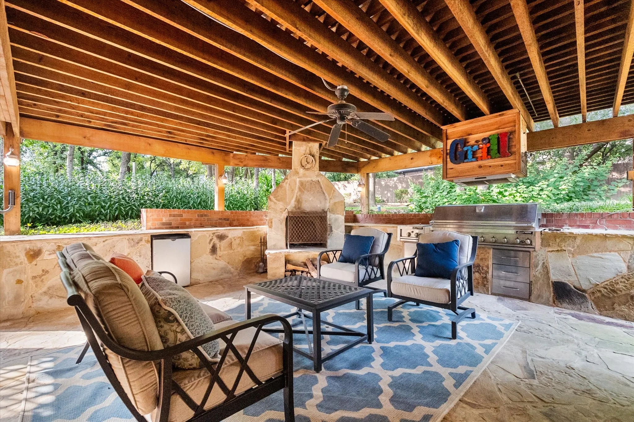 outdoor living space with fireplace, refrigerator and large built-in grill