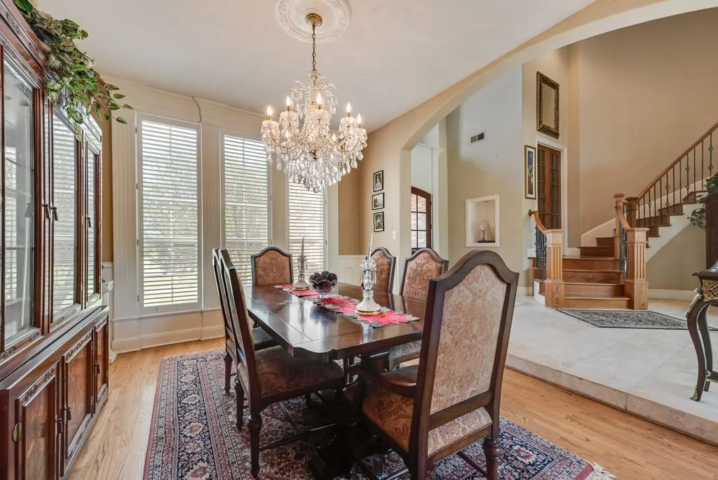 Elegant dining area featuring wood-finish flooring and chandelier.