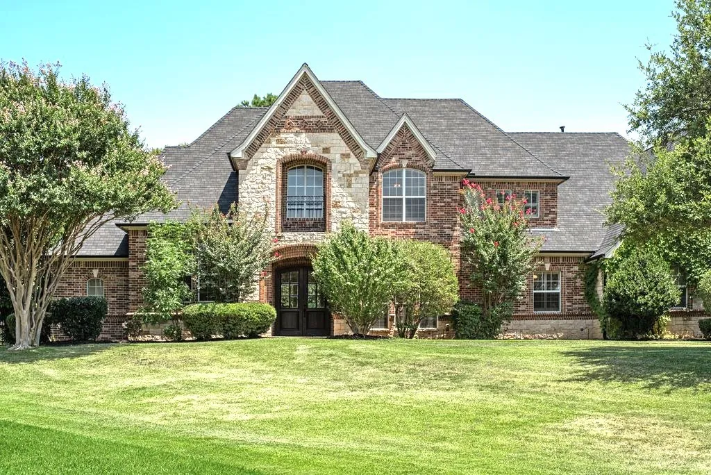 Brick and stone exterior with a prominent gabled roofline, arched entry, and double entry doors