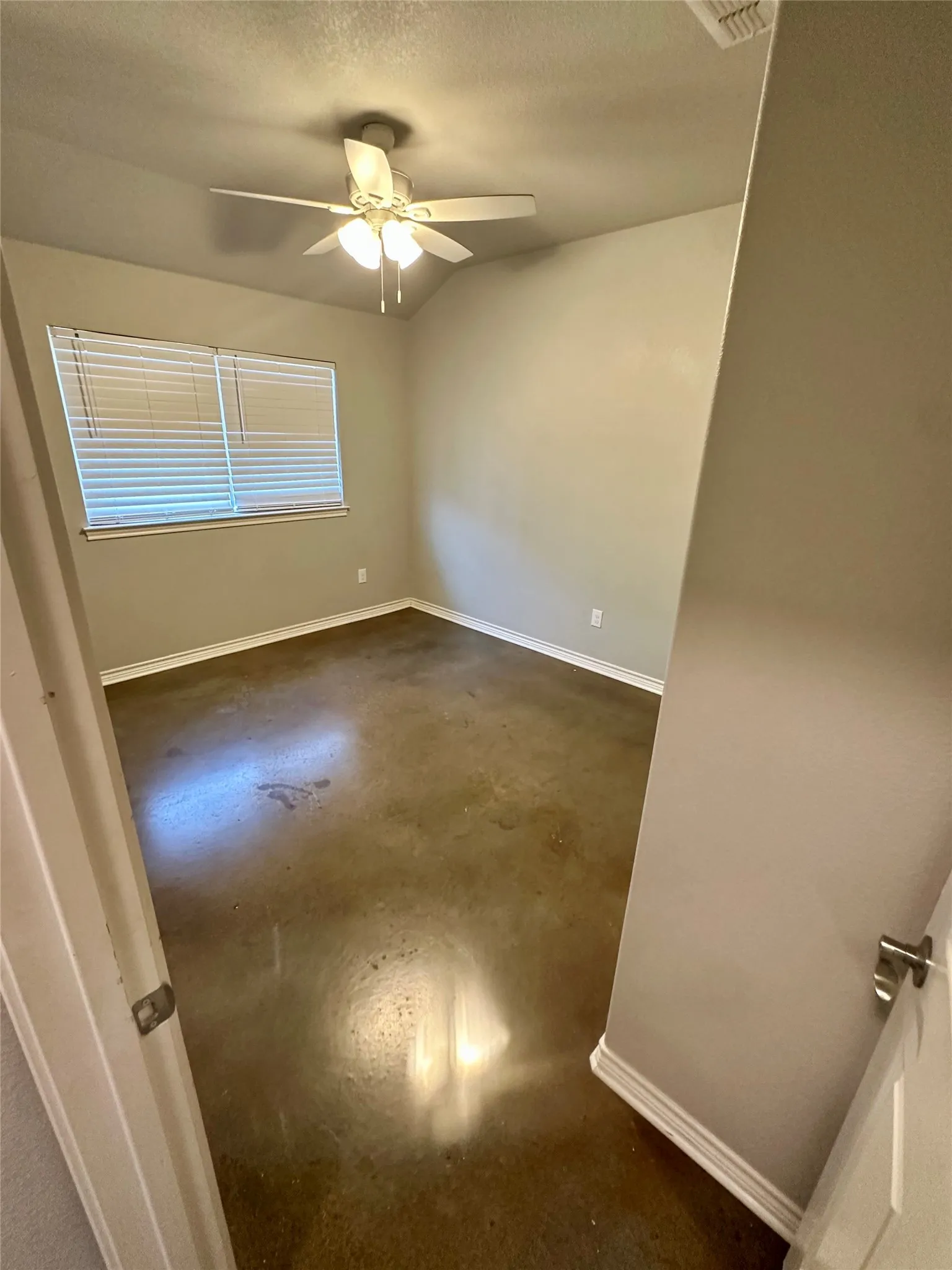 Featuring concrete flooring, ceiling fan, baseboards, and a textured ceiling