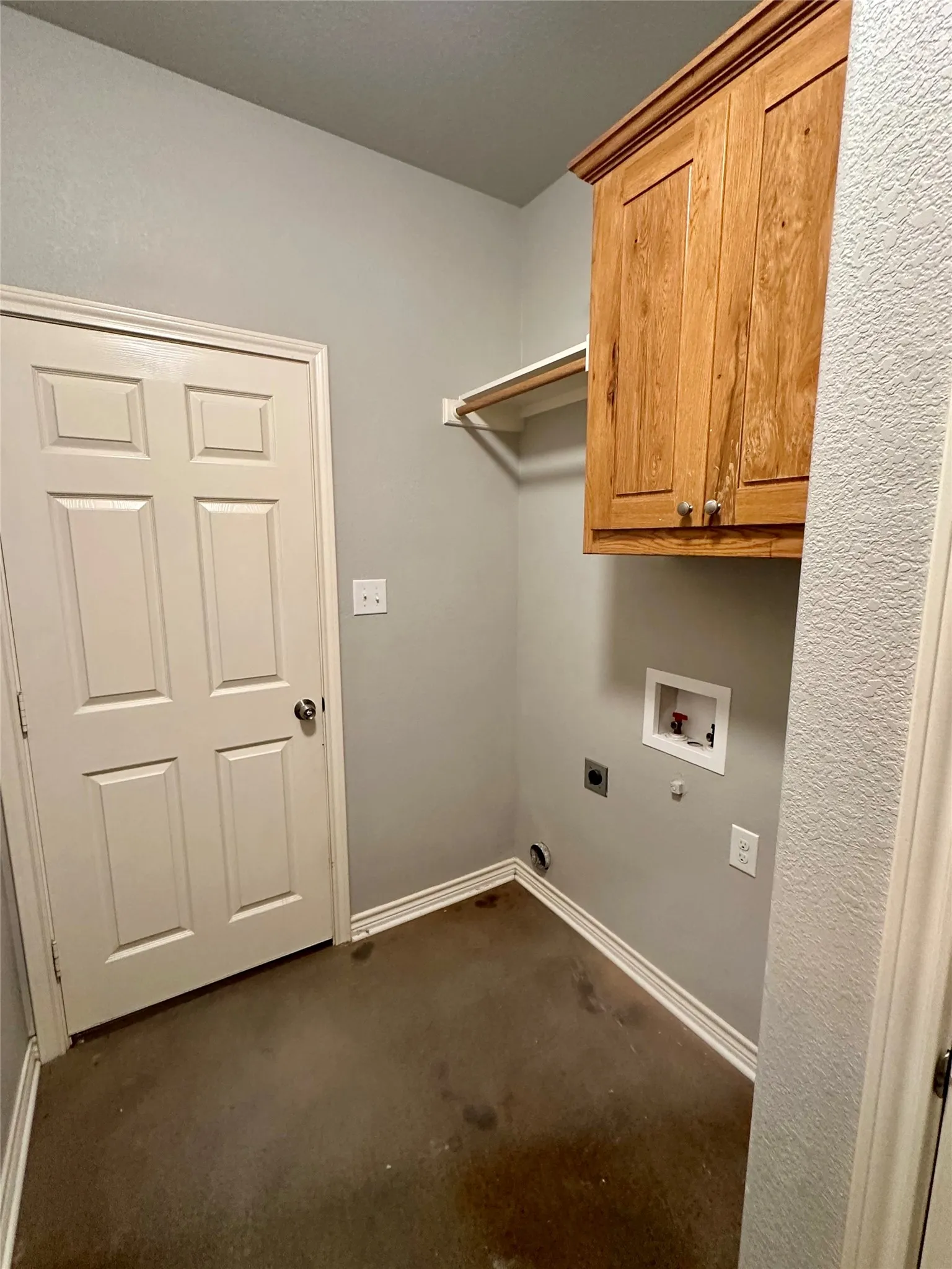 Washroom with hookup for an electric dryer, hookup for a washing machine, cabinet space, dark colored carpet, and baseboards
