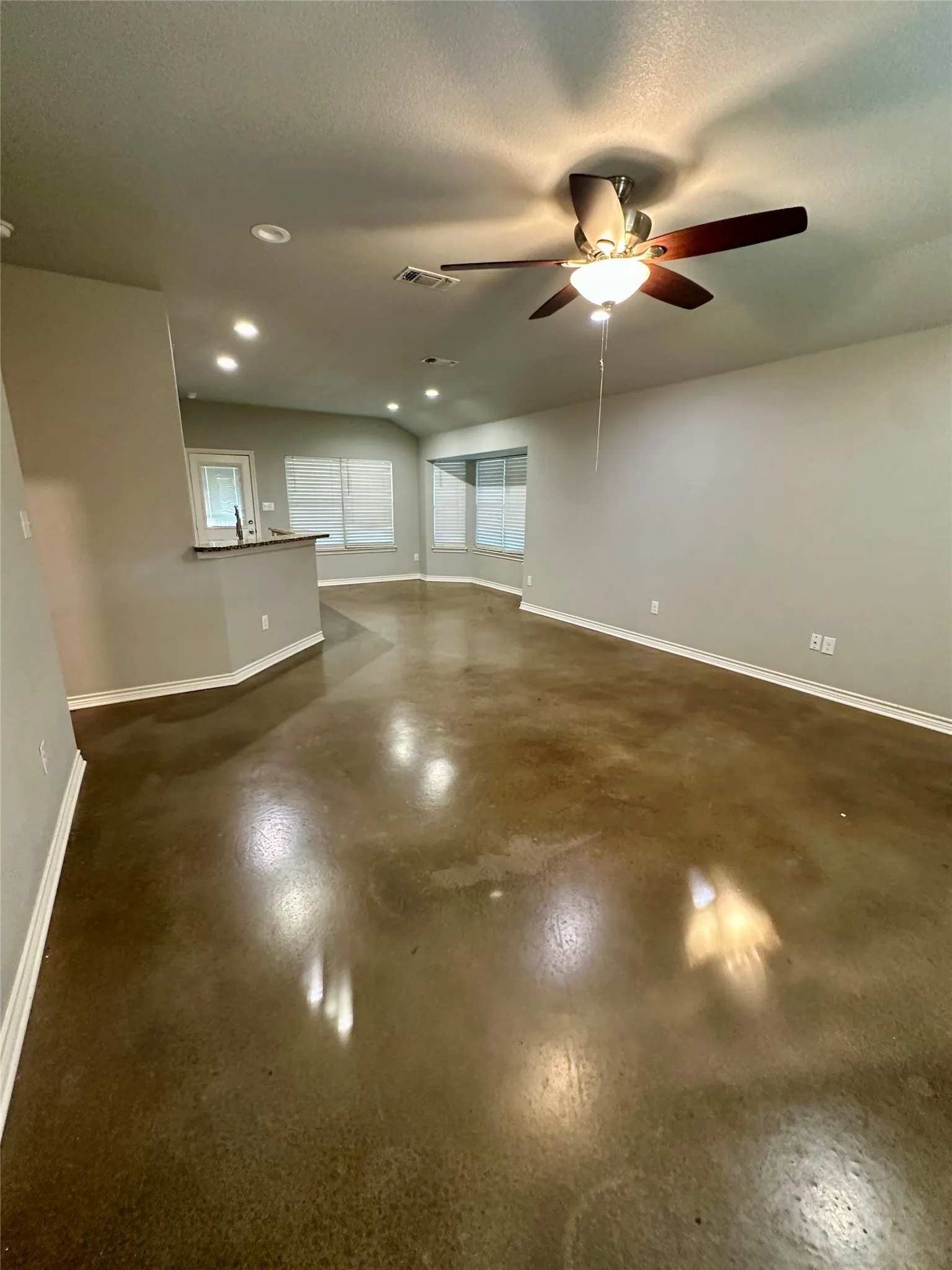 Living room featuring baseboards, a ceiling fan, finished concrete floors, and recessed lighting