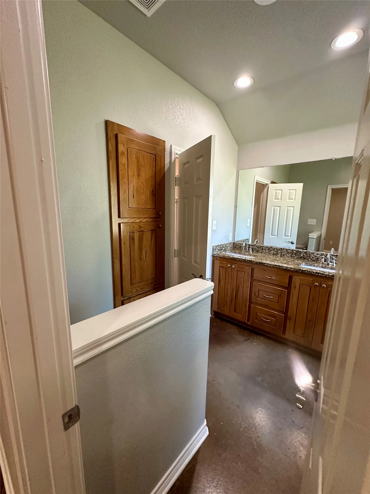 Bathroom featuring concrete floors, double vanity, recessed lighting, and toilet